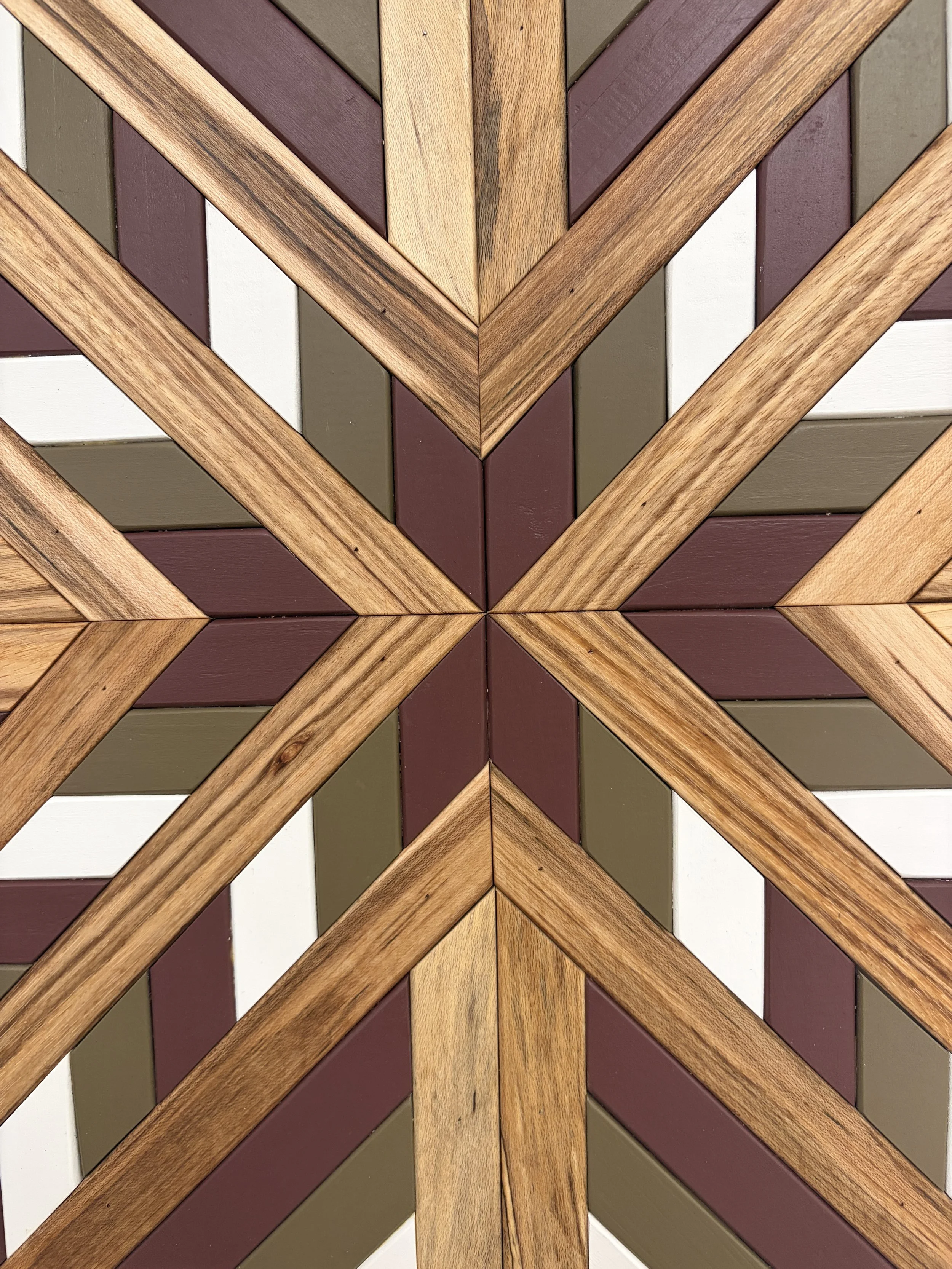 Detailed view of a handcrafted framed wooden mosaic in white, pink, and green paint with natural stains.