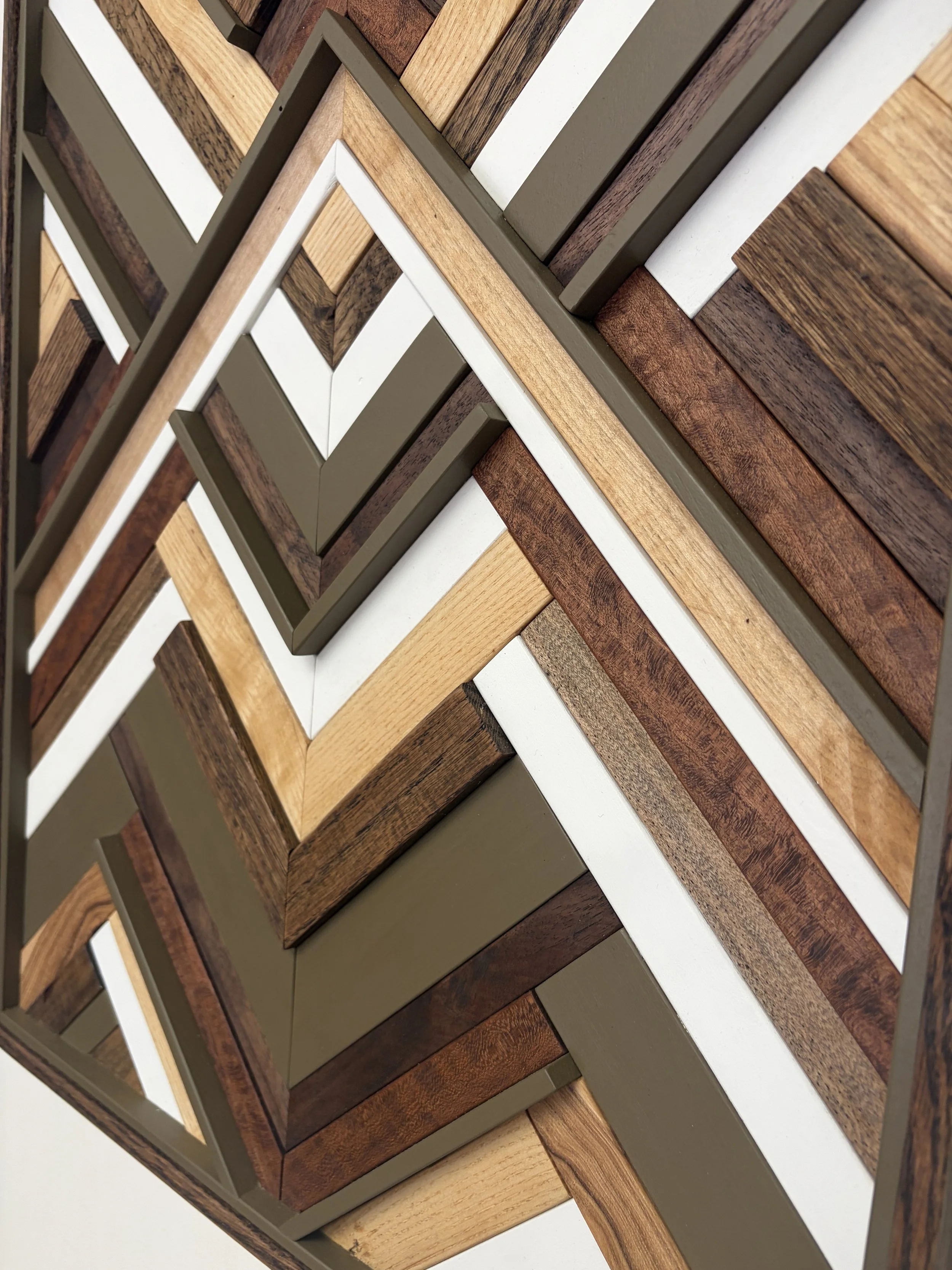 Close up view of a handcrafted framed wooden mosaic in white and light olive green paint with natural, espresso, and red mahogany stains.