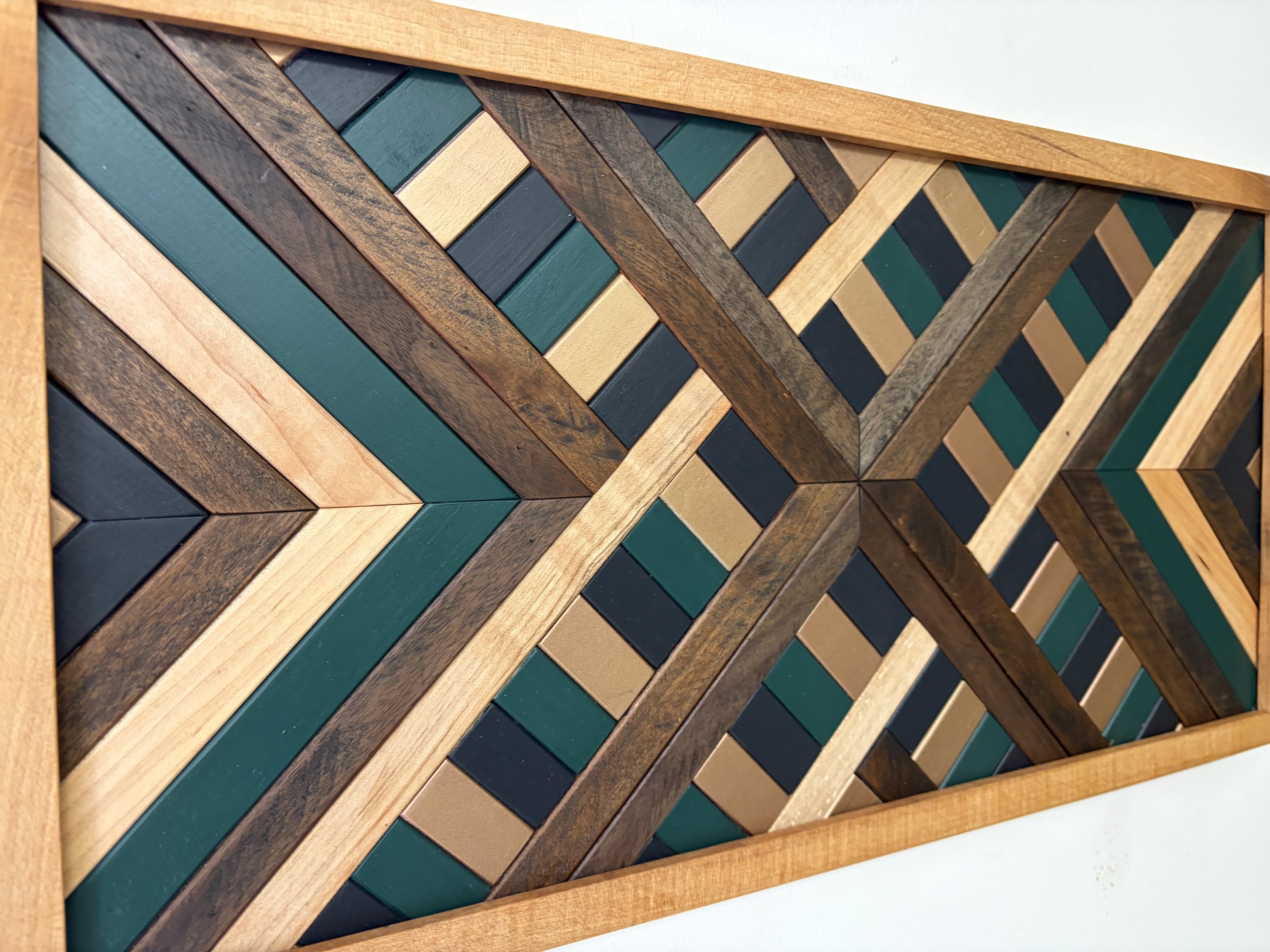 Side view of a handcrafted framed wooden mosaic in black, green, and gold paint with natural and espresso stains.