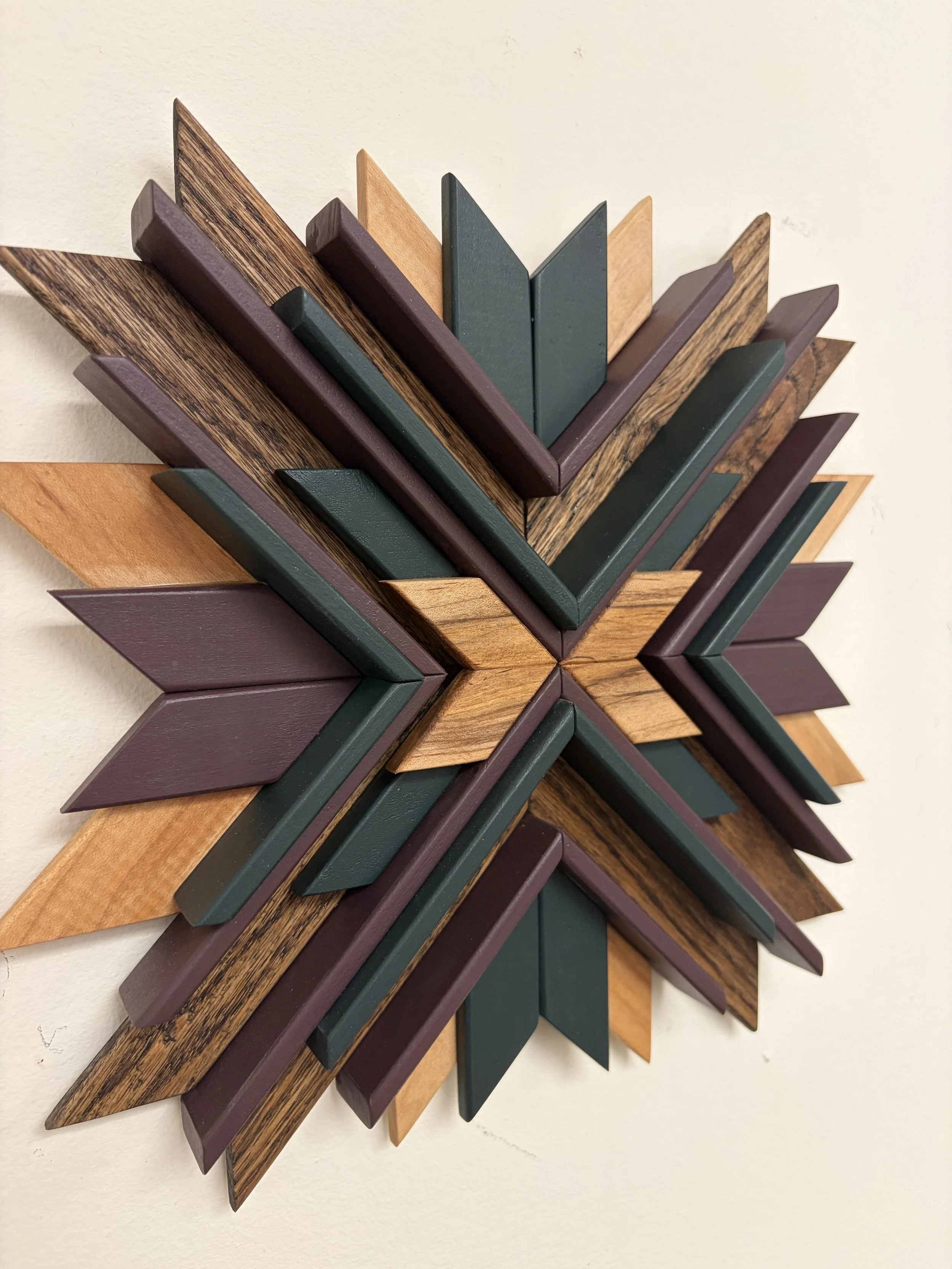 Side view of a wooden sunburst style mosaic in green and purple paint with natural and espresso stains.