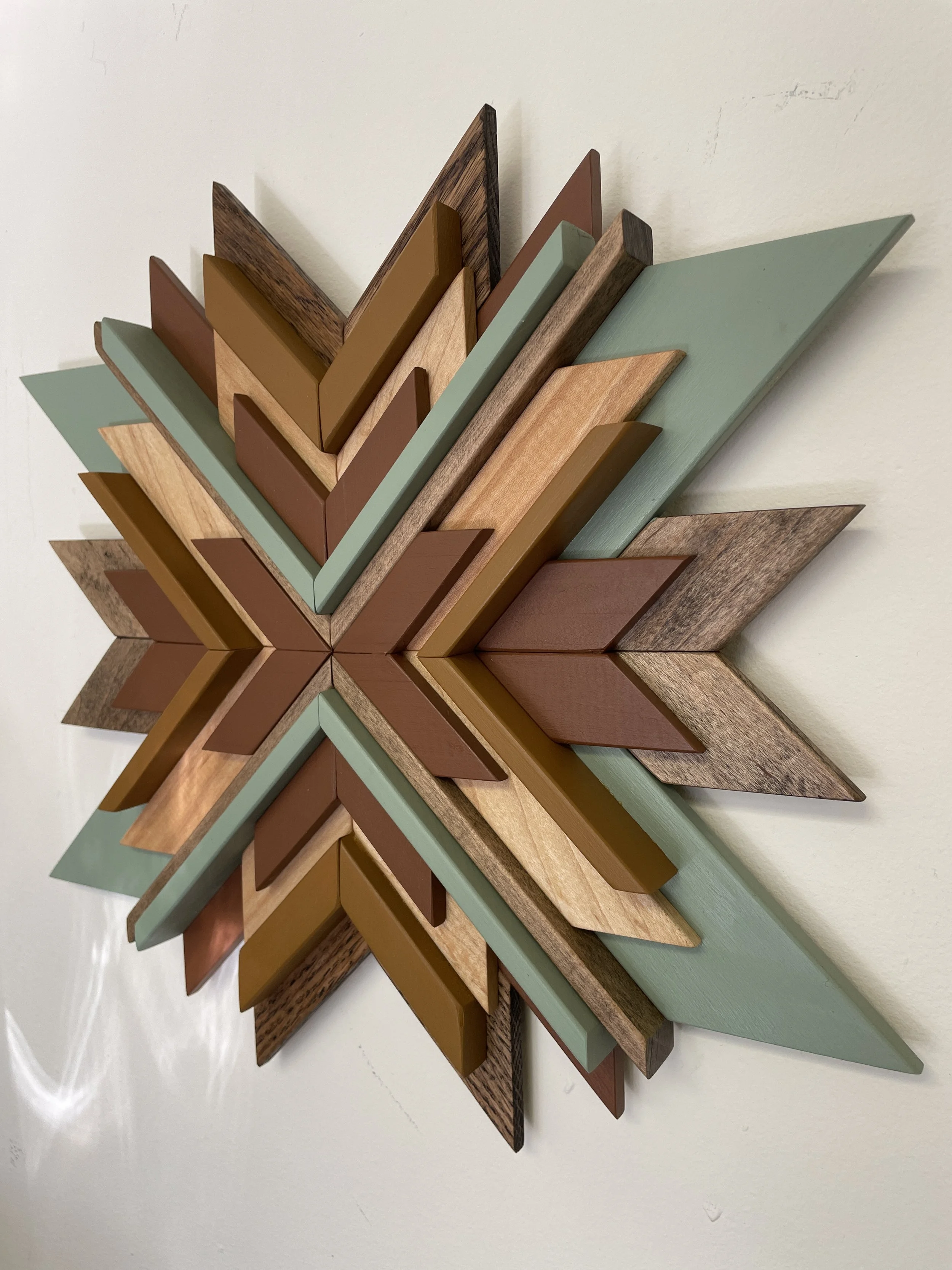 Side view of a handcrafted wooden sunburst mosaic in green, yellow, and orange paints with natural and espresso stains.