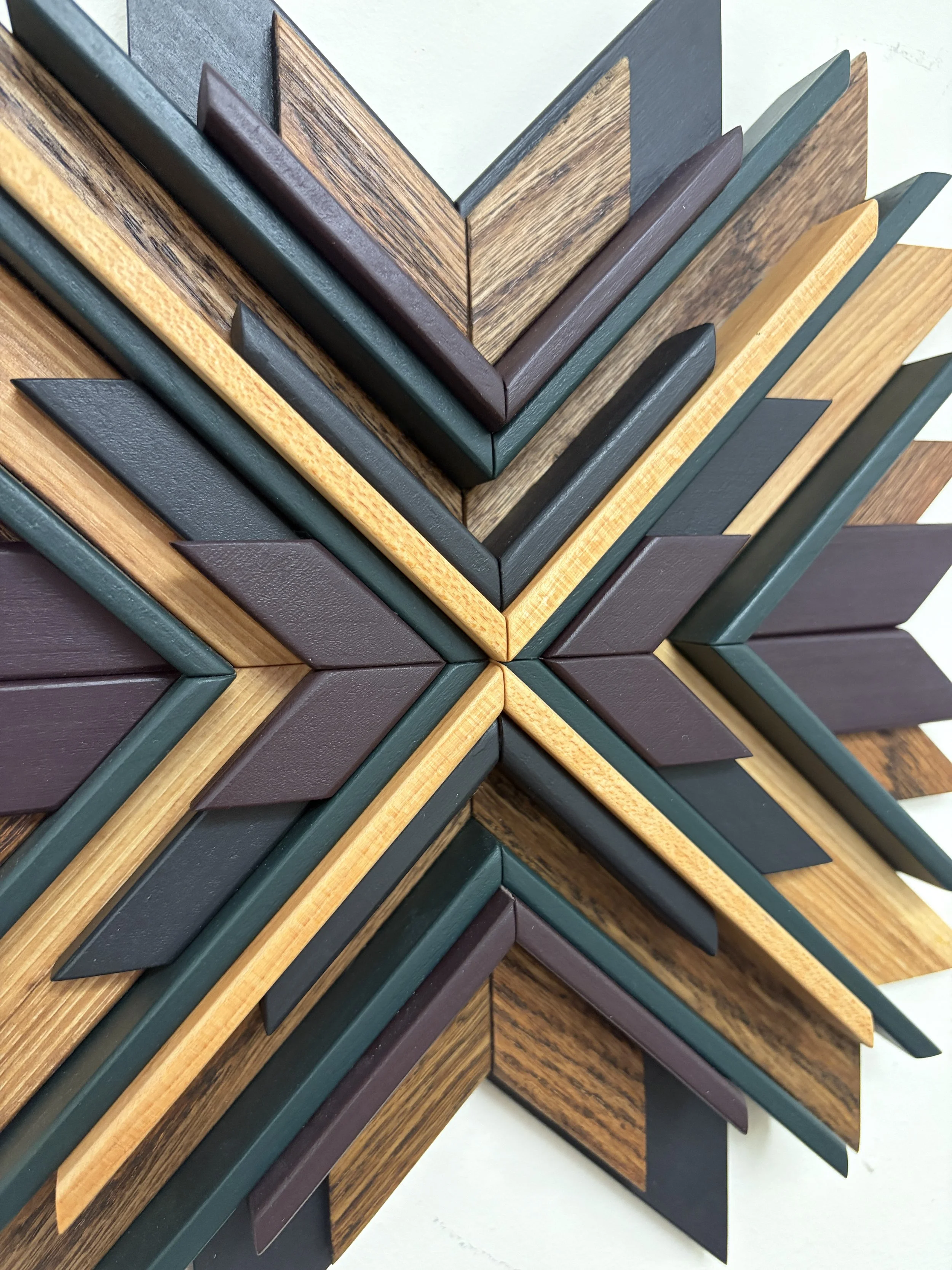 Close up view of a wooden mosaic in black, purple, and green paint with natural and espresso stains.