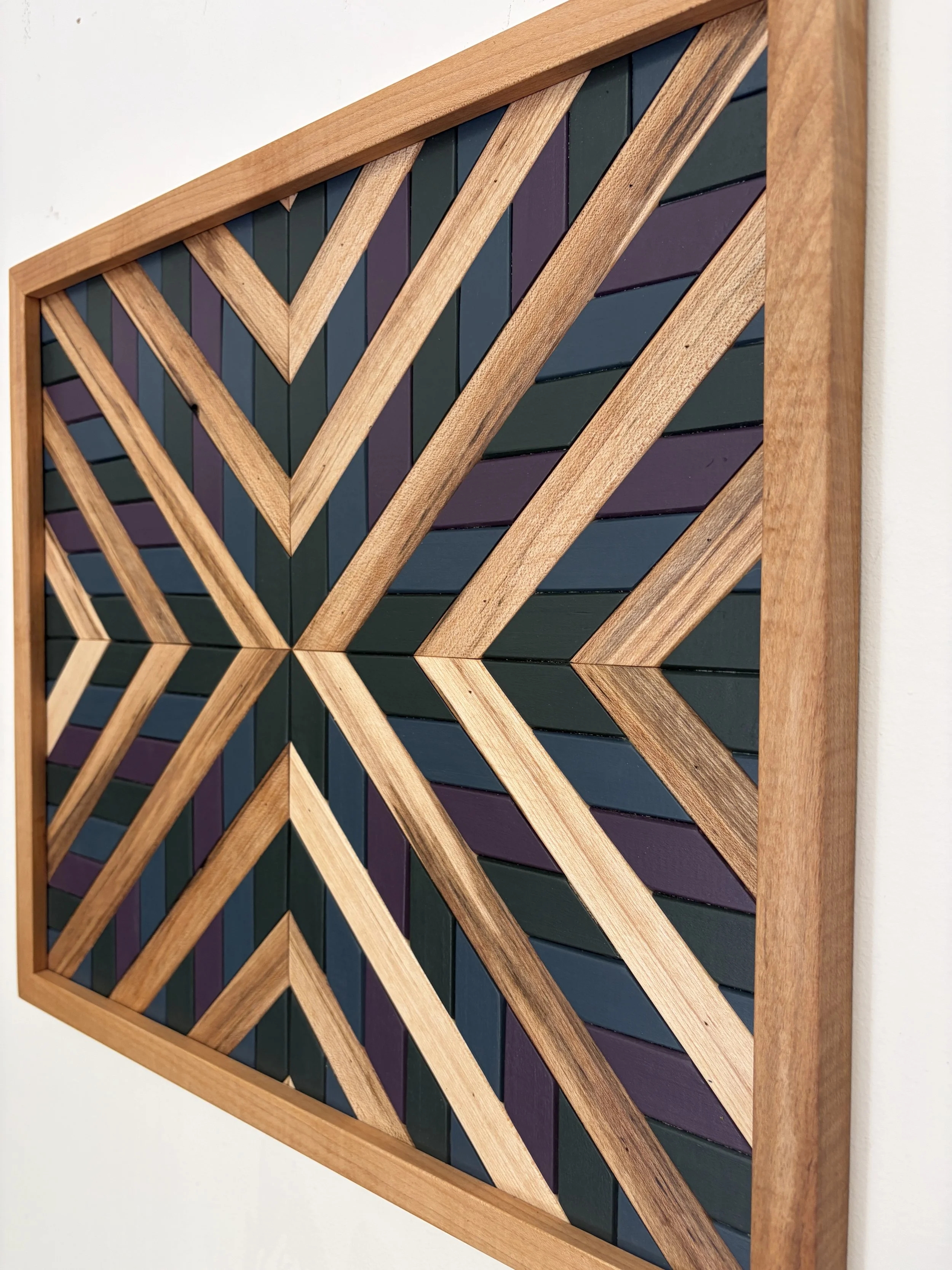 Side view of a handcrafted framed wooden mosaic in green, purple, and blue paint with natural stains.