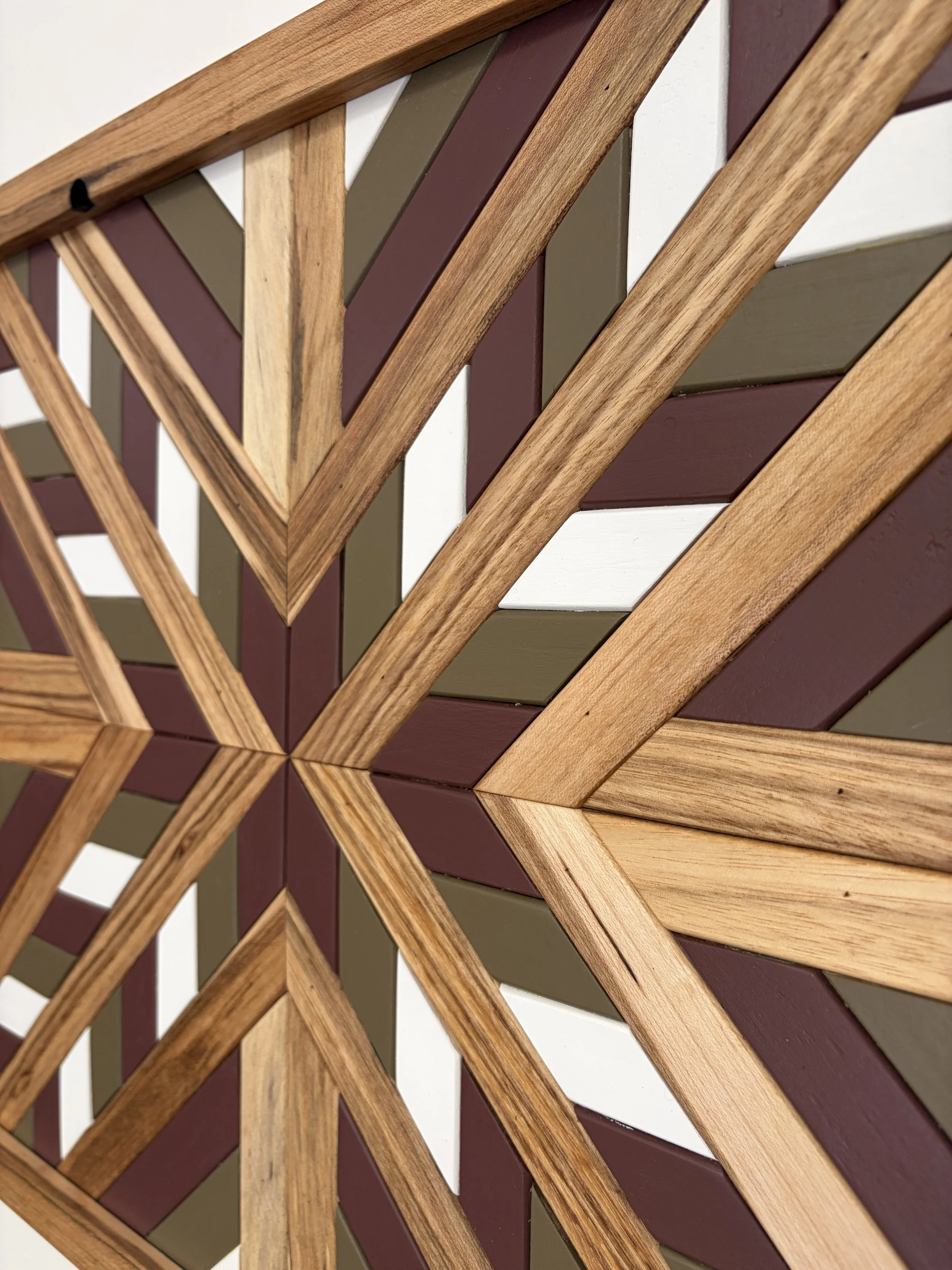 Close up side view of a handcrafted framed wooden mosaic in white, pink, and green paint with natural stains.