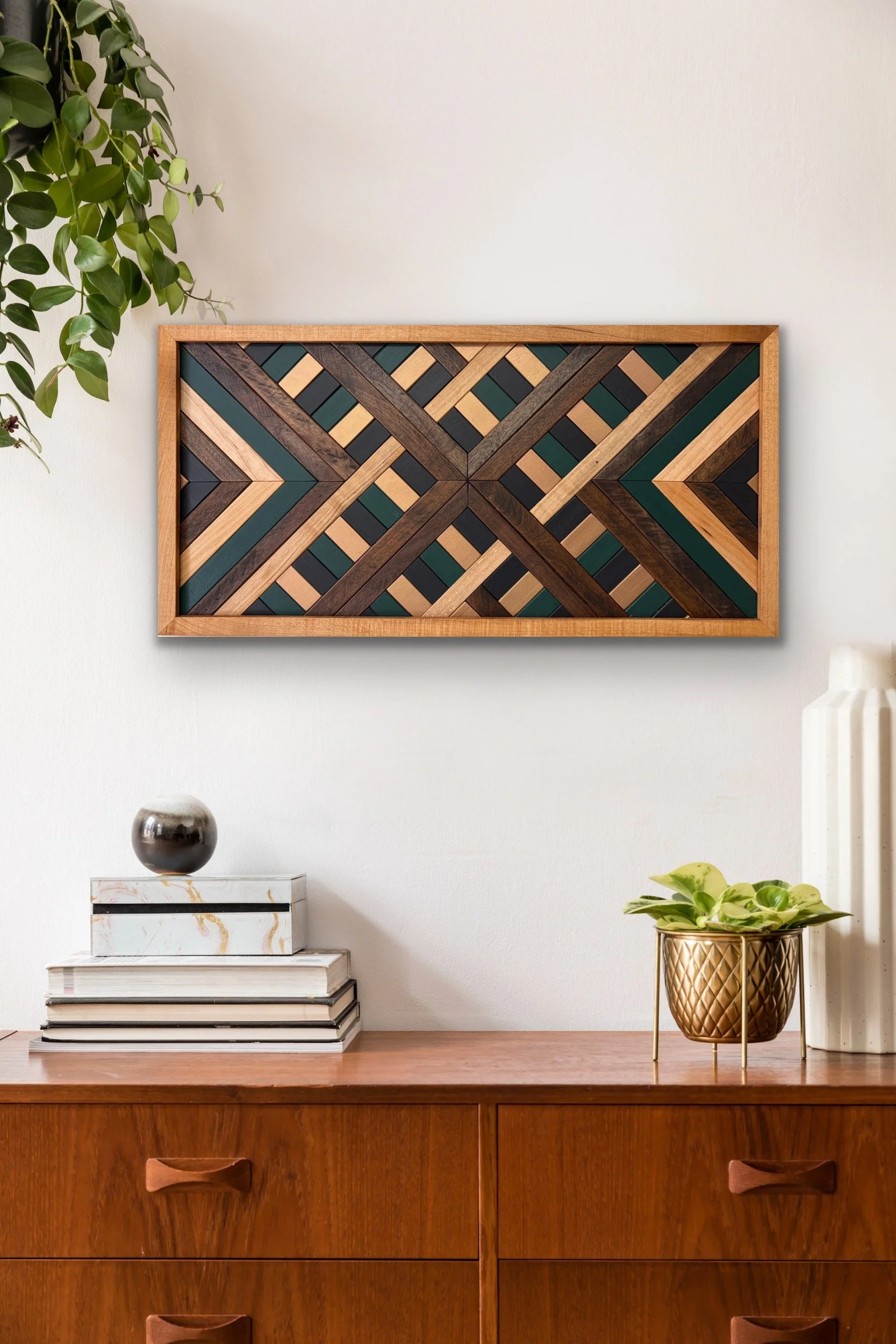Handcrafted framed wooden mosaic in black, green, and gold paint with natural and espresso stains hanging on a wall.
