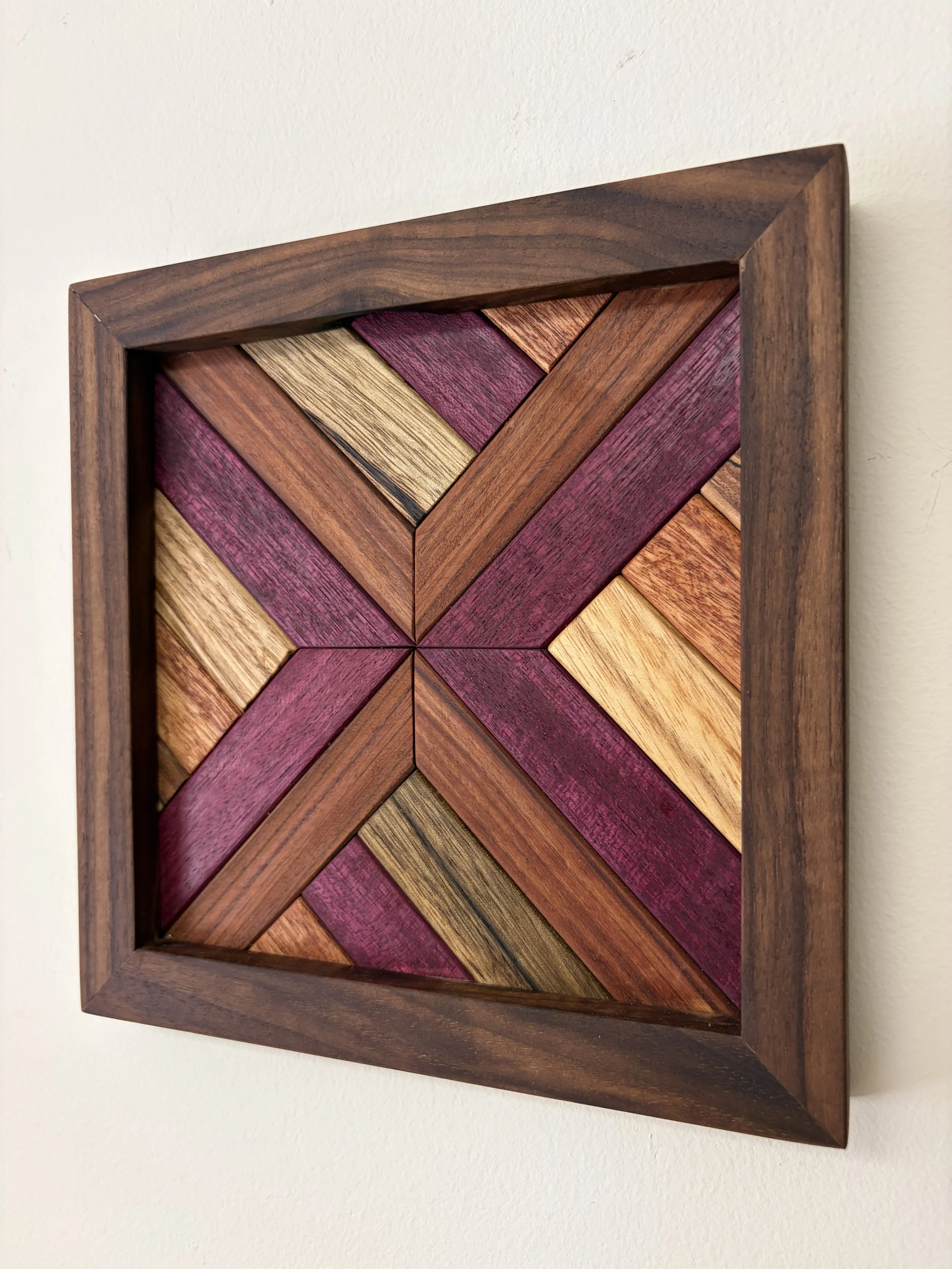 Angled view of a handcrafted framed wooden mosaic made from various exotic woods.