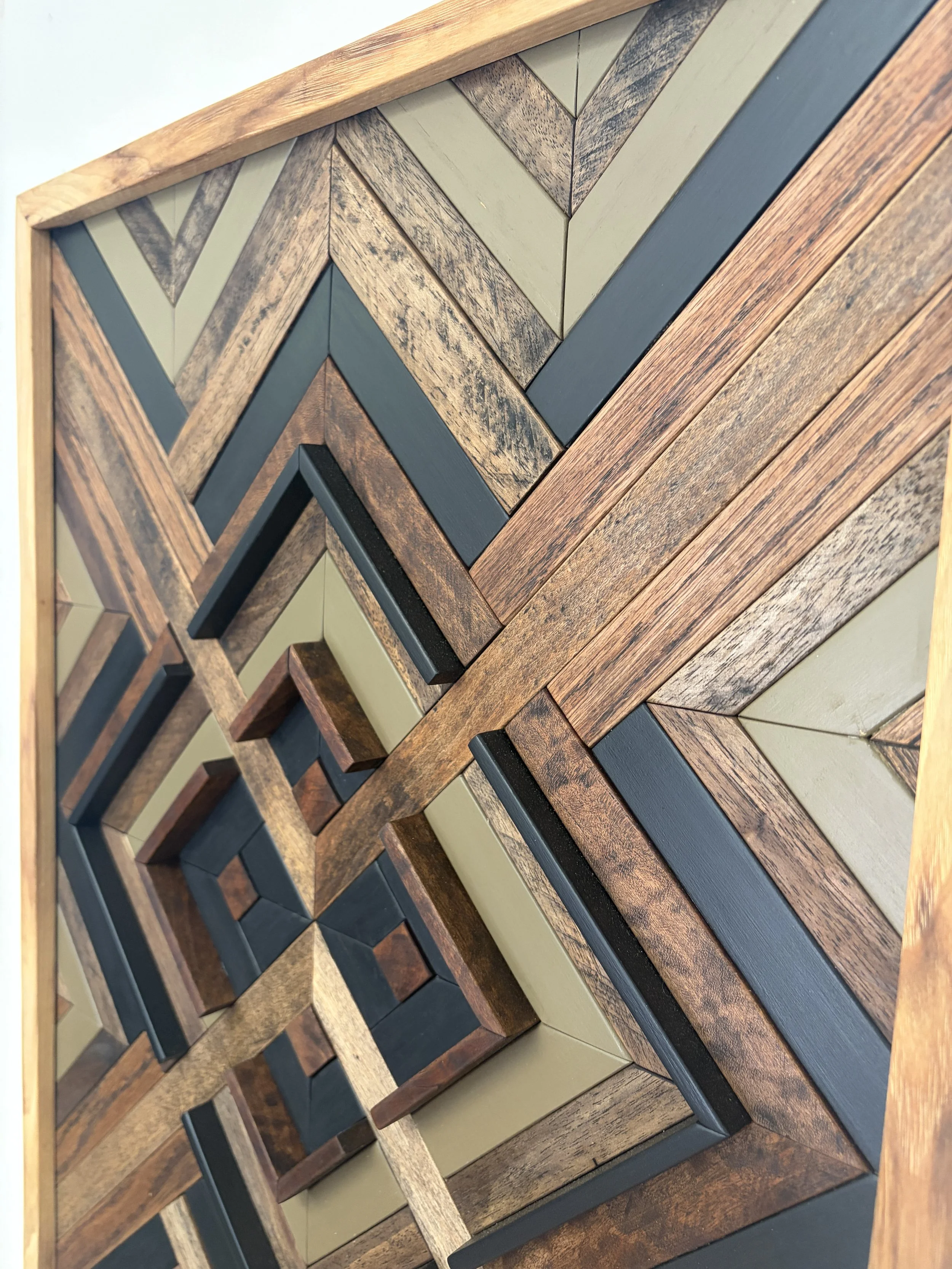 Close up side view of a handcrafted framed wooden mosaic in black and green paint with an espresso stains.