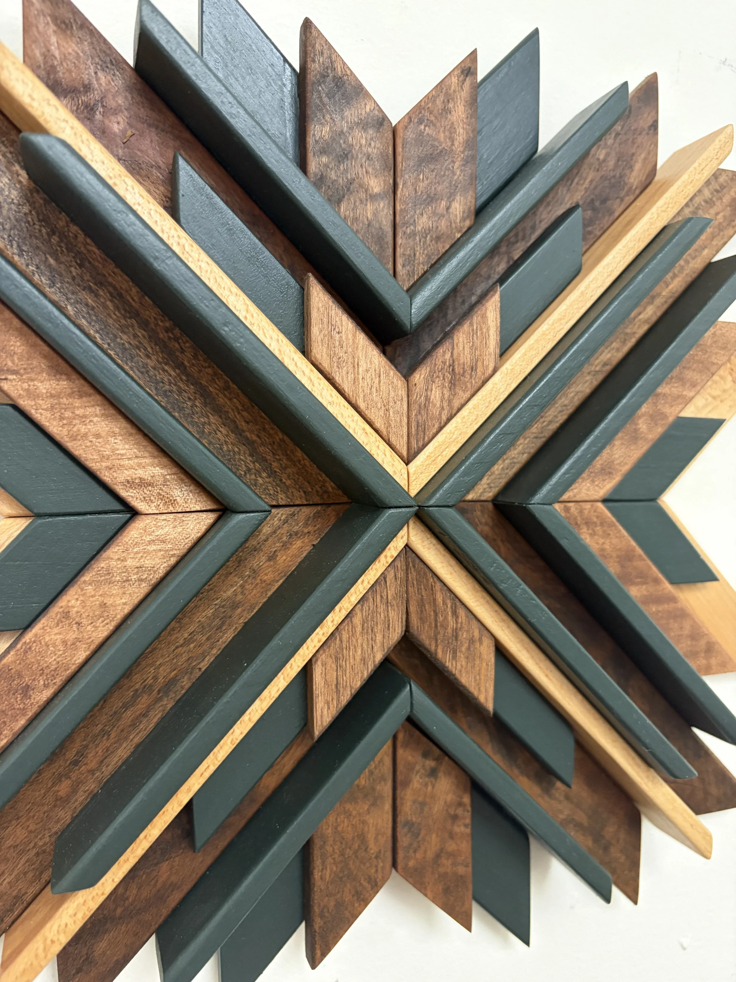 Close up view of a wooden sunburst style mosaic in green paint with light and dark stains.