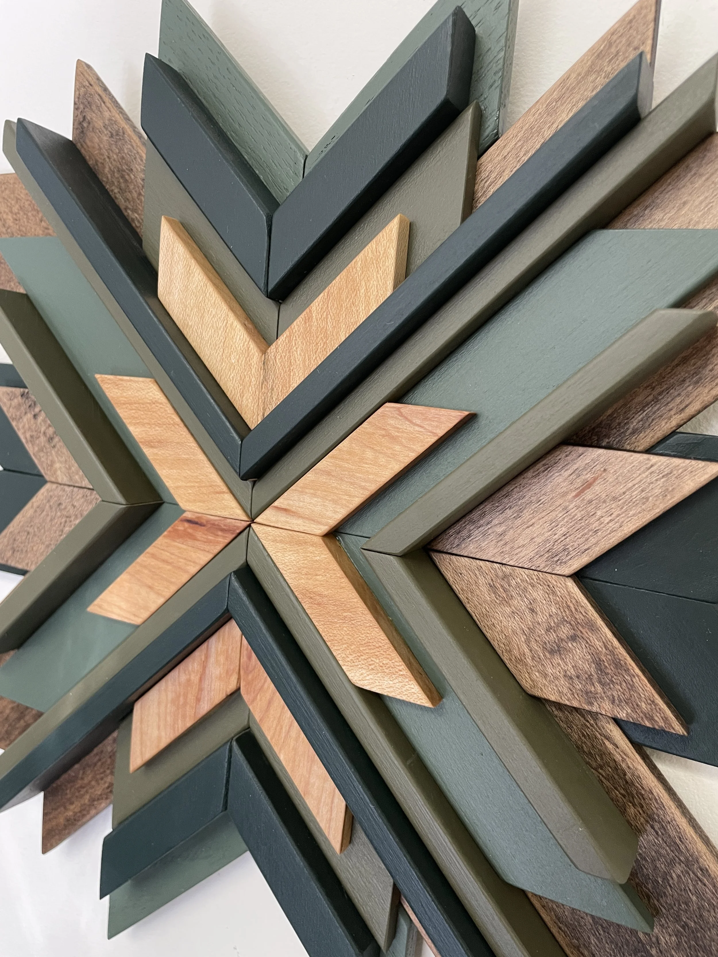 Detailed view of a handcrafted wooden sunburst mosaic in various green paints with natural and espresso stains.