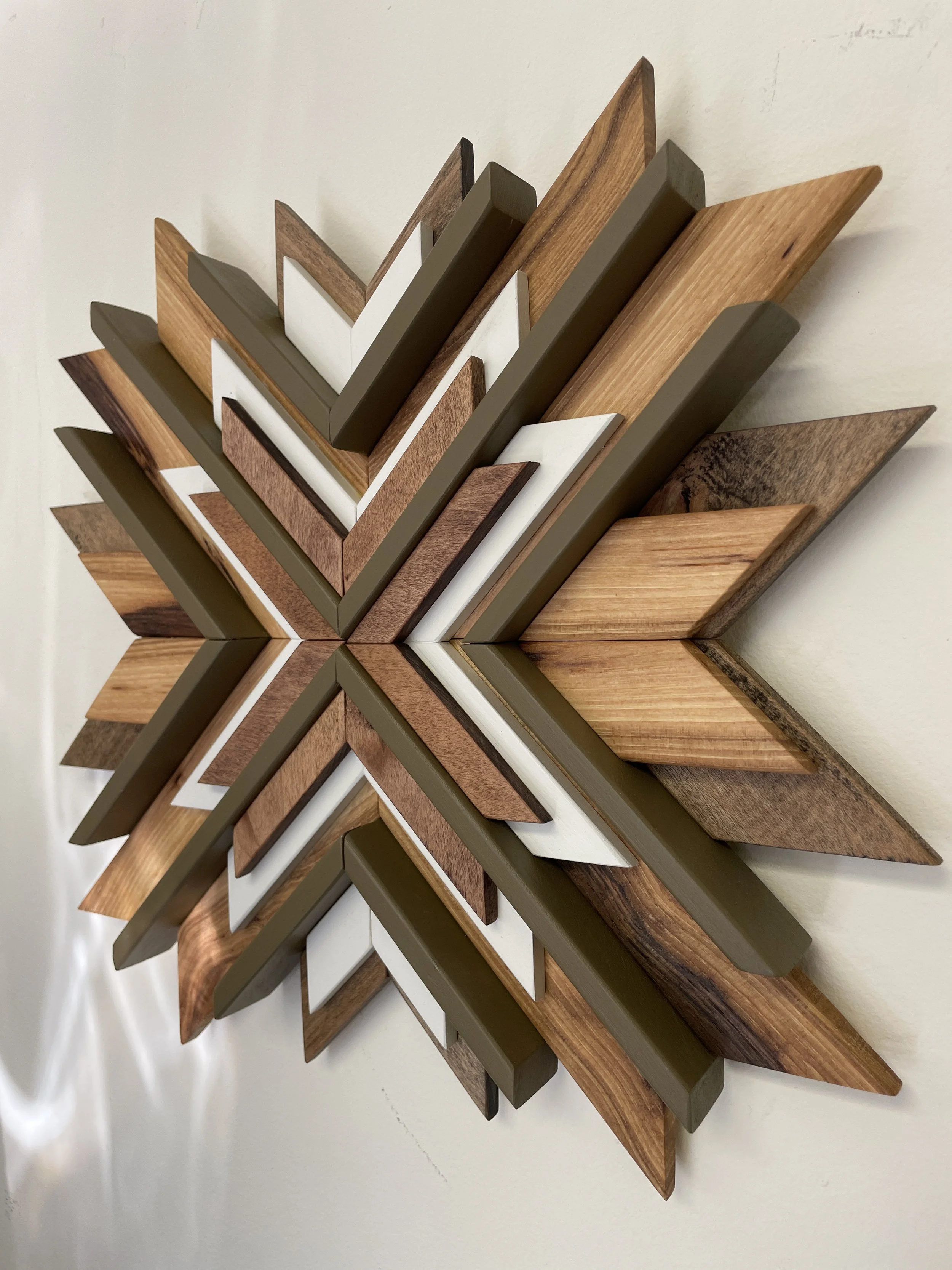 Side view of a handcrafted sunburst style wooden mosaic in white and green paints with natural and dark stains.