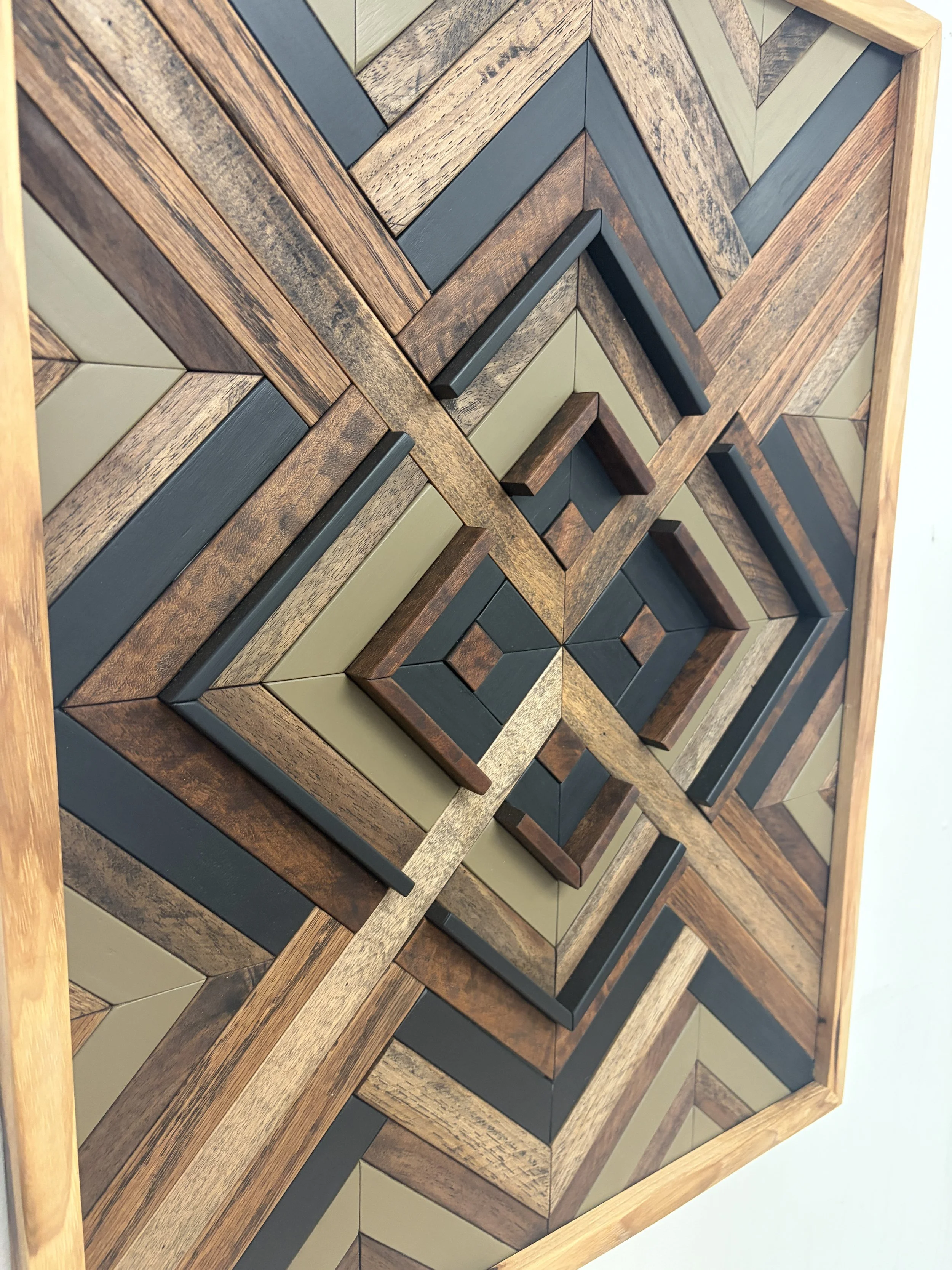Close up view of a handcrafted framed wooden mosaic in black and green paint with an espresso stains.