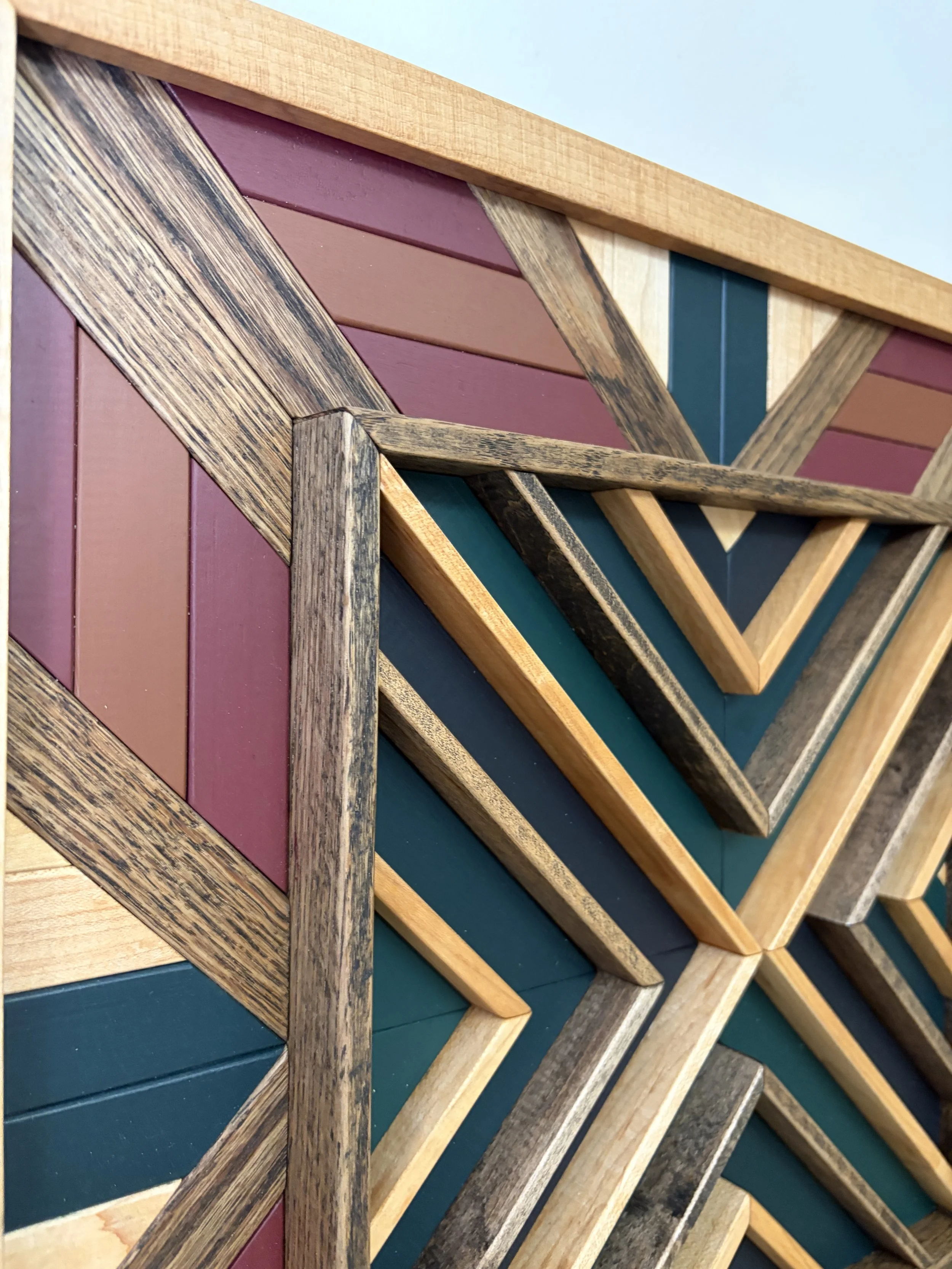 Detailed view of a handcrafted framed wooden mosaic in black, green, teal, pink, and orange paint with natural and espresso stains.