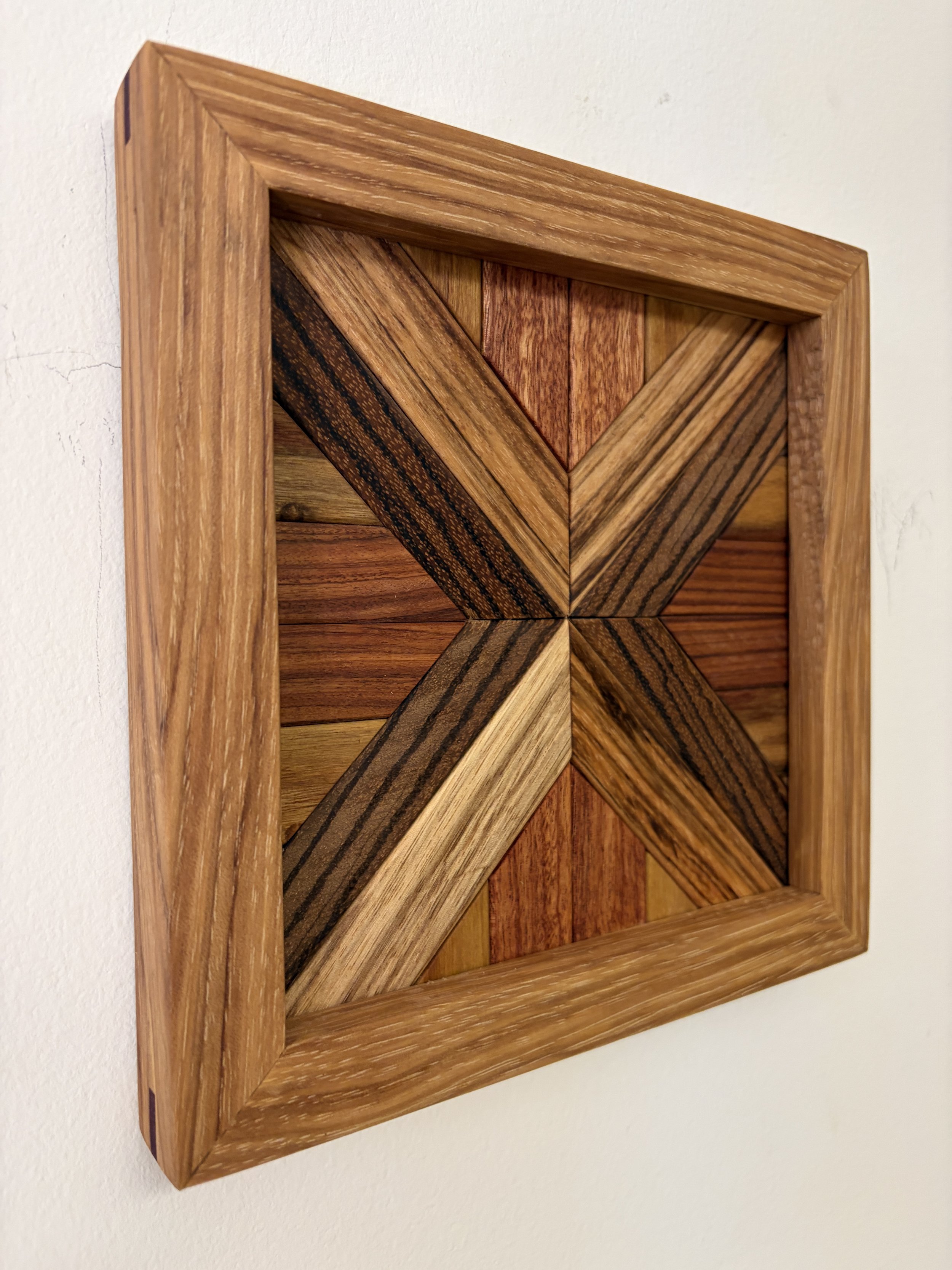 Angled view of a handcrafted framed wooden mosaic made from various exotic woods.
