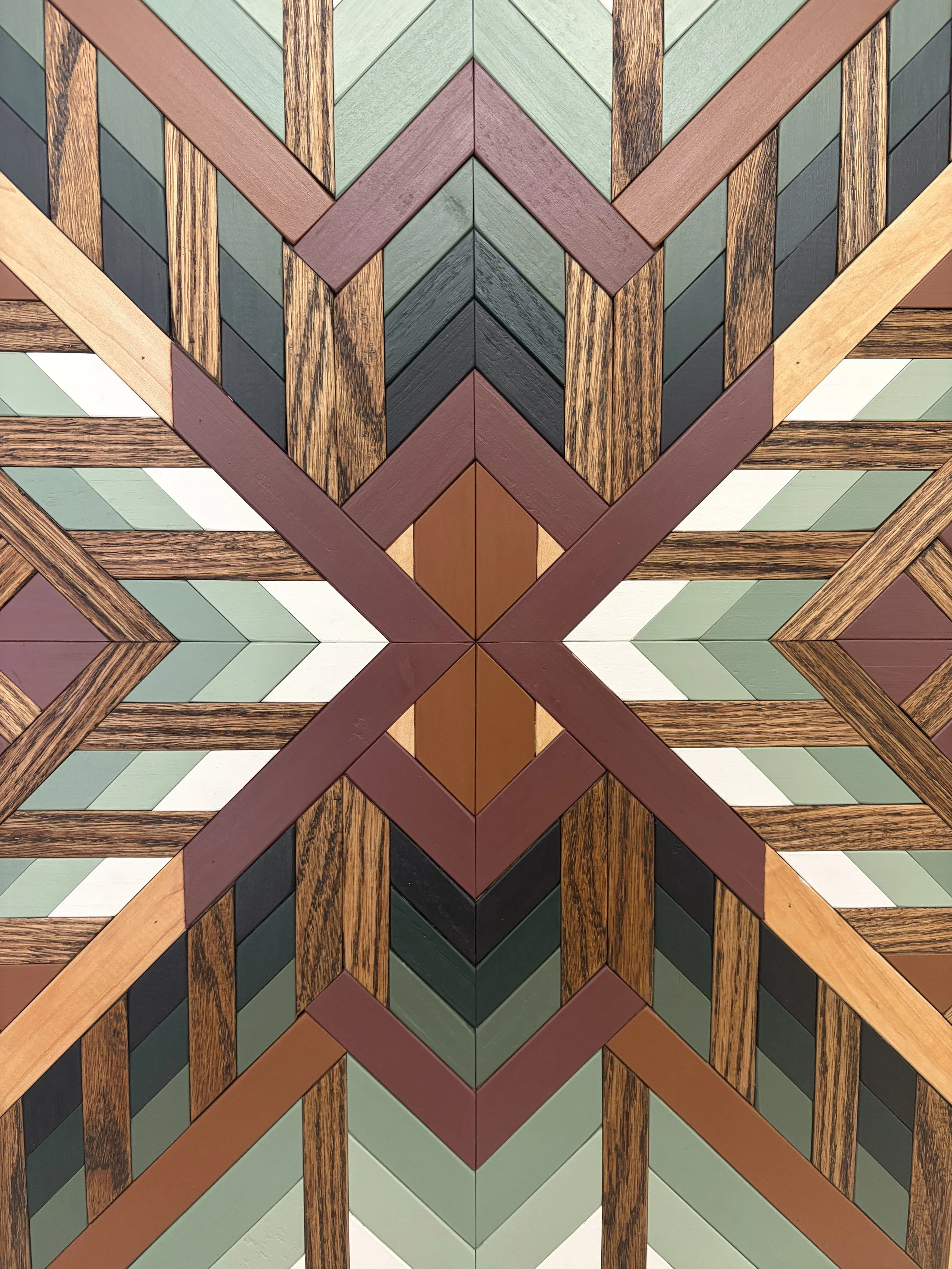 Detailed view of a handcrafted framed wooden mosaic in black, white, pink, orange, and various green paints with natural and espresso stains.