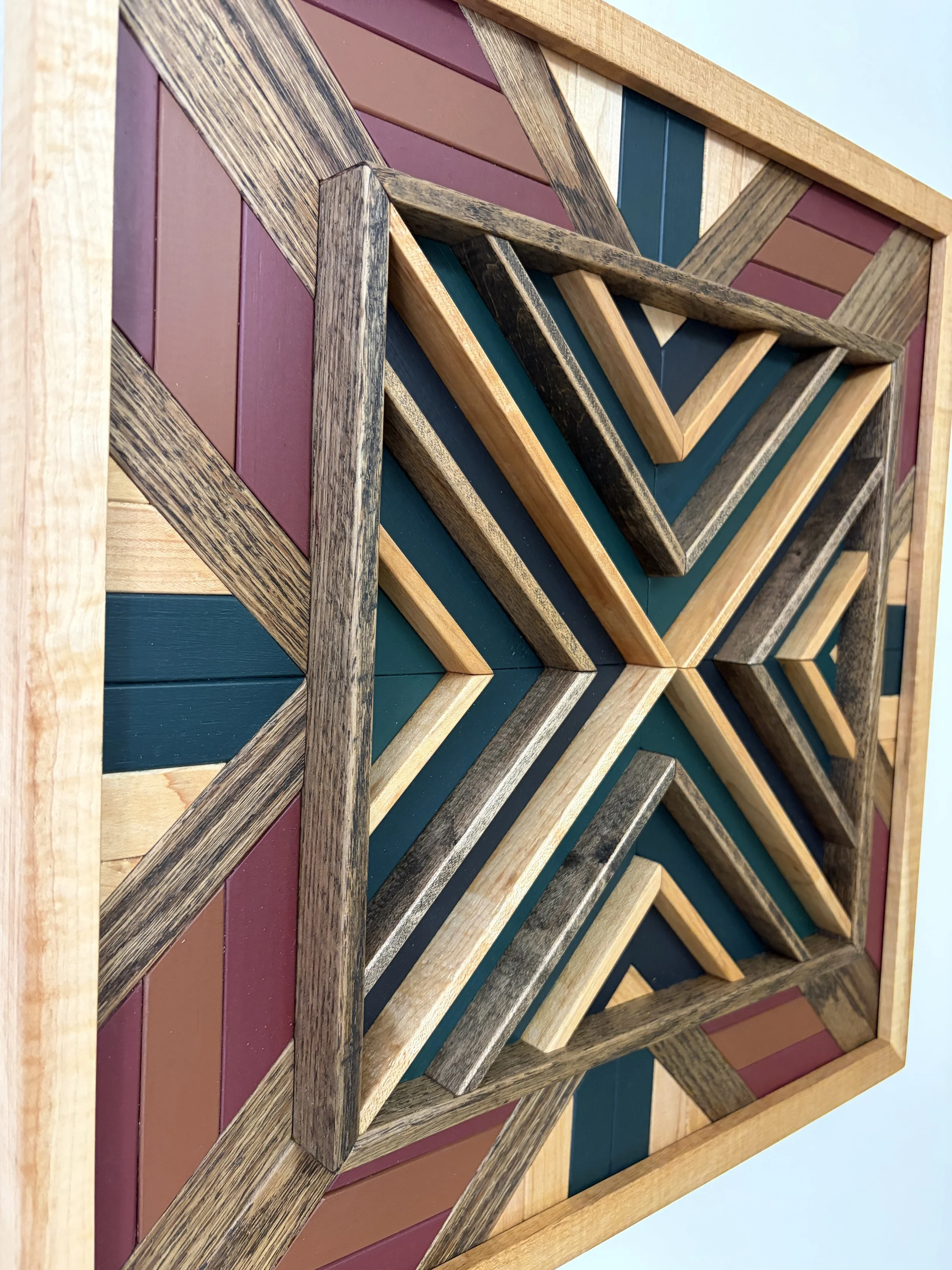 Side view of a handcrafted framed wooden mosaic in black, green, teal, pink, and orange paint with natural and espresso stains.