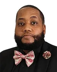 Portrait of a man wearing a suit against a gray textured background with text reading 'Commissioner Mr. Eddie Gonzalez'."