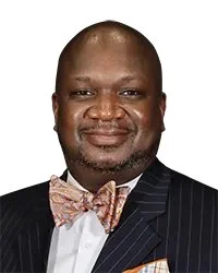 Portrait of a man in a suit and tie labeled as "Commissioner Mr. Joel D. Ramirez" against a grayscale nature background.