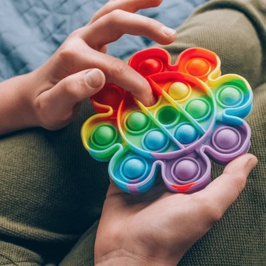 child playing with rainbow pop-it fidget toy