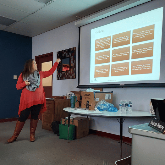Instructor standing in front of classroom presenting using a projector