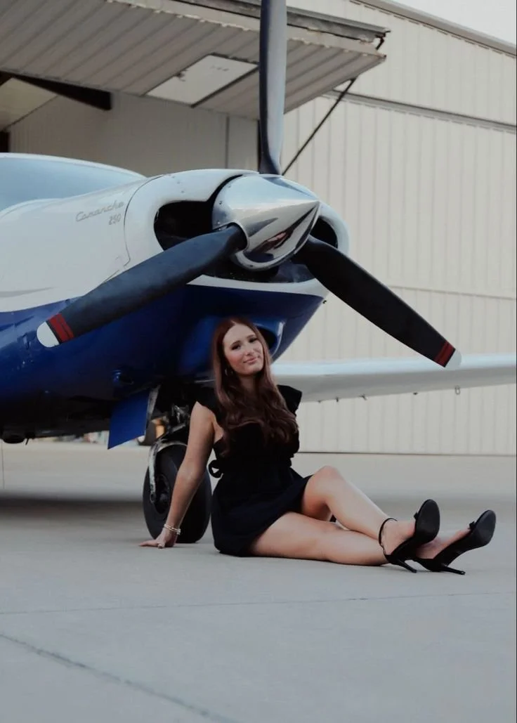 Pose direction:
“Sit near the front of the plane and lean back on one hand. Bend one leg and let the other angle out naturally. Keep your shoulders relaxed and look off to the side first.”

Movement cue:
“Look away, smile softly, then laugh down towa