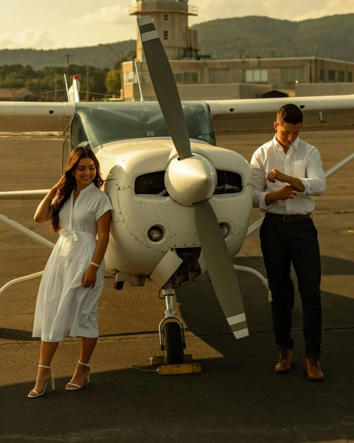 Stand slightly off-center from the nose of the plane. Adjust your sleeve, hair, or gown like you’re casually getting ready, then slowly look back toward the camera