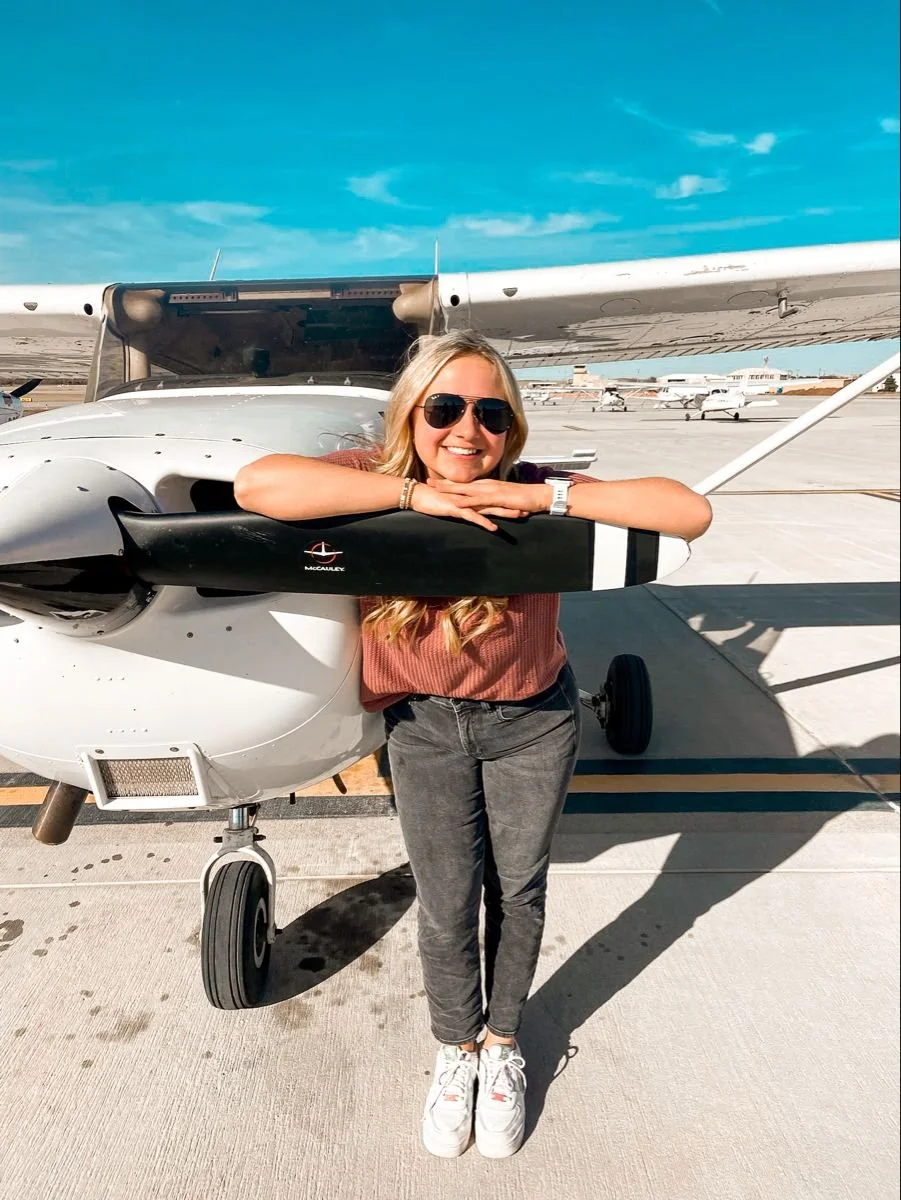 Pose direction:
“Rest your forearms gently across the front area near the propeller, then place your chin on your hands. Keep your shoulders soft and give me an easy, relaxed smile.”

Movement cue:
“Smile at me first, then look off to the side for a 