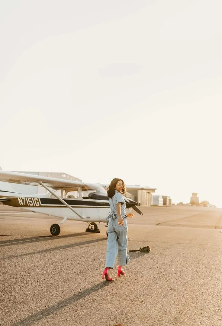 Pose direction:
“Stand beside the plane and turn your body slightly toward the camera. Pop one heel up behind you, hold your diploma or cap naturally, and give me a bright celebration smile.”

Movement cue:
“Pop the heel up, relax it down, then pop i