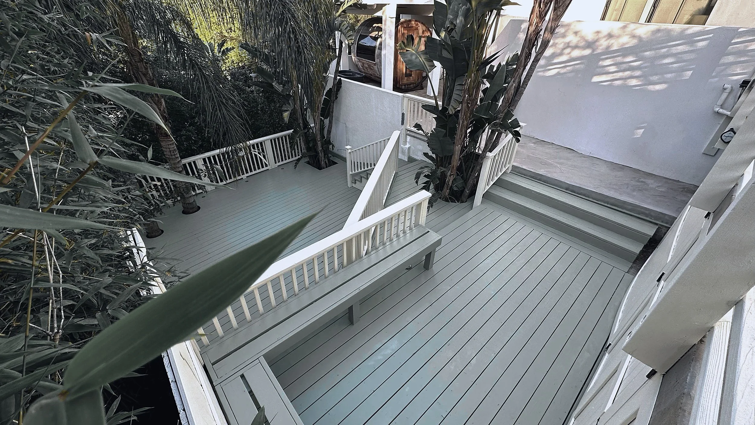 Painted deck with a built-in bench and railing, stepping down from the concrete terrace.