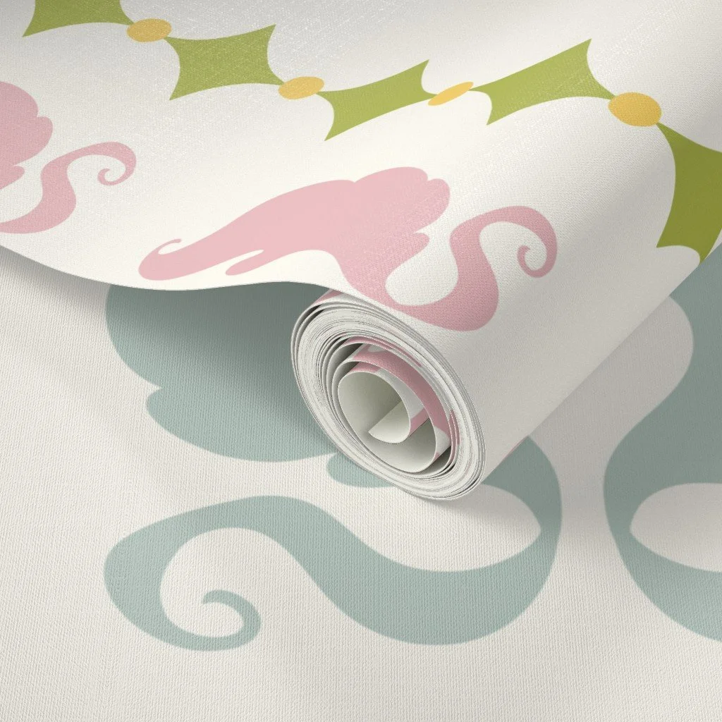 A rolled-up sheet of wrapping paper with pink and green Christmas-themed designs, including holly leaves and swirling patterns, resting on a matching surface.