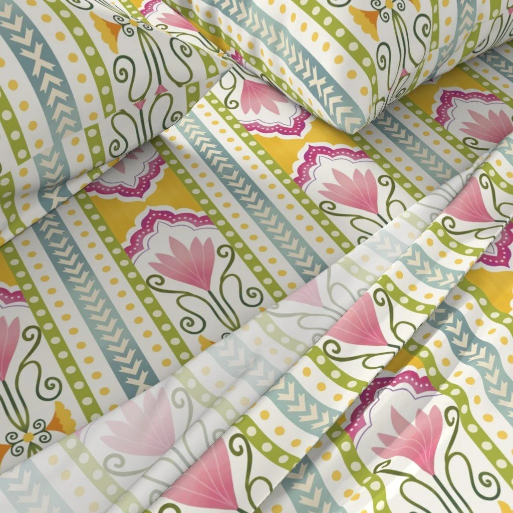 Close-up of fabric with a colorful, floral pattern featuring pink, yellow, green, and blue geometric and floral designs.