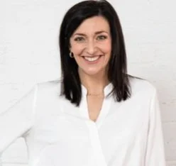 Person smiling in a white shirt against a white background