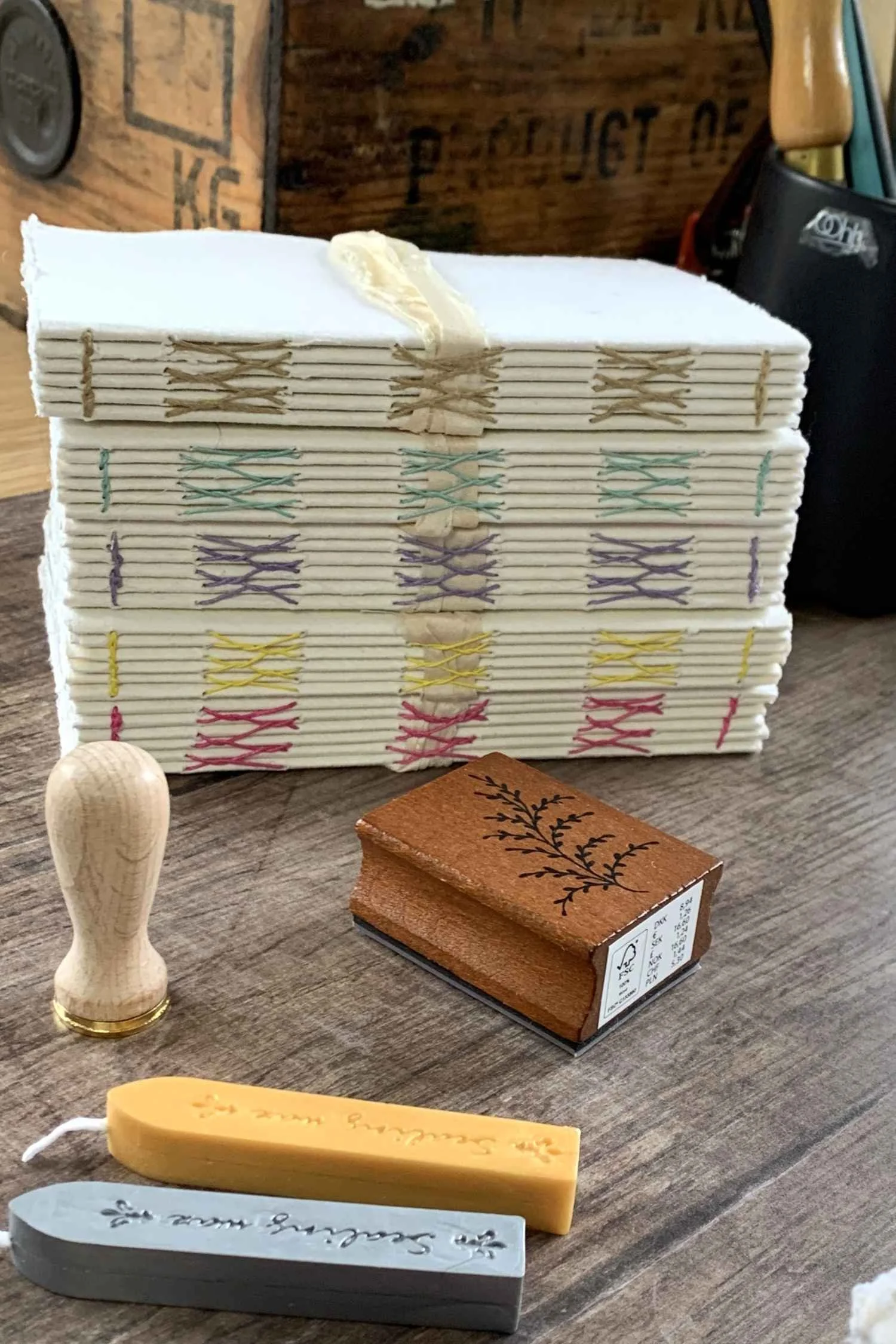 A stack of chunky books with a deckled edge and coloured stitching on the spine