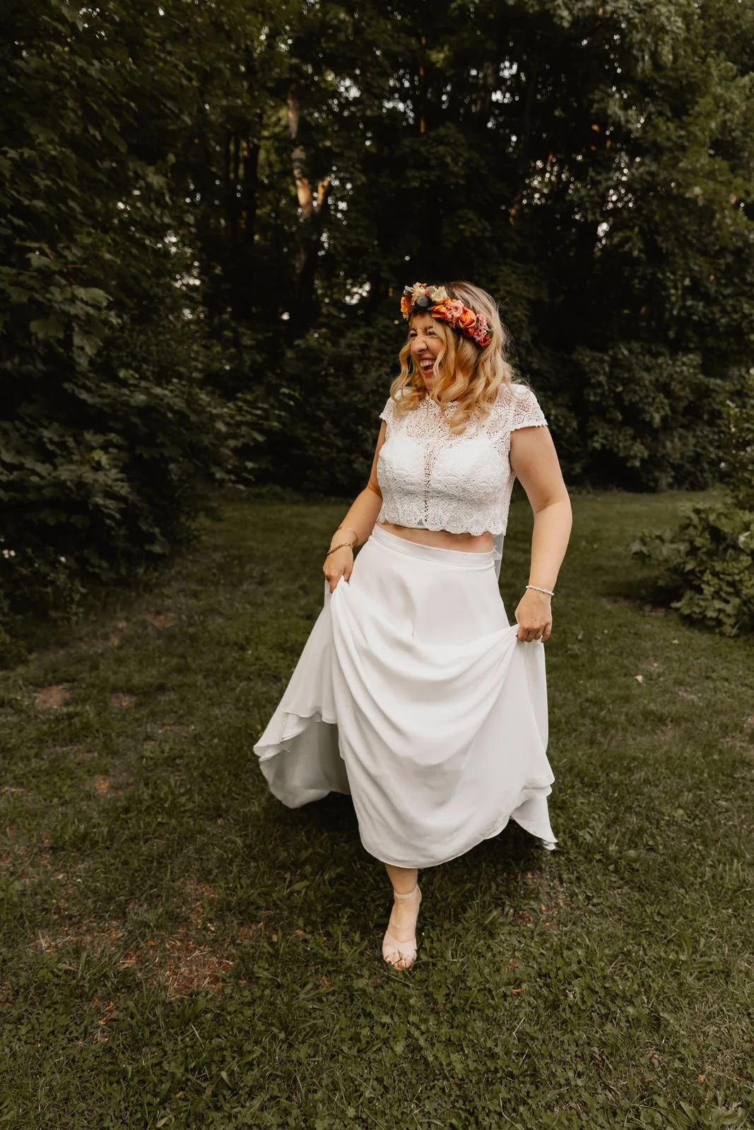 Lächelnde Braut mit Blumenkranz spaziert im Hochzeitskleid durch den Park in Lüneburg
