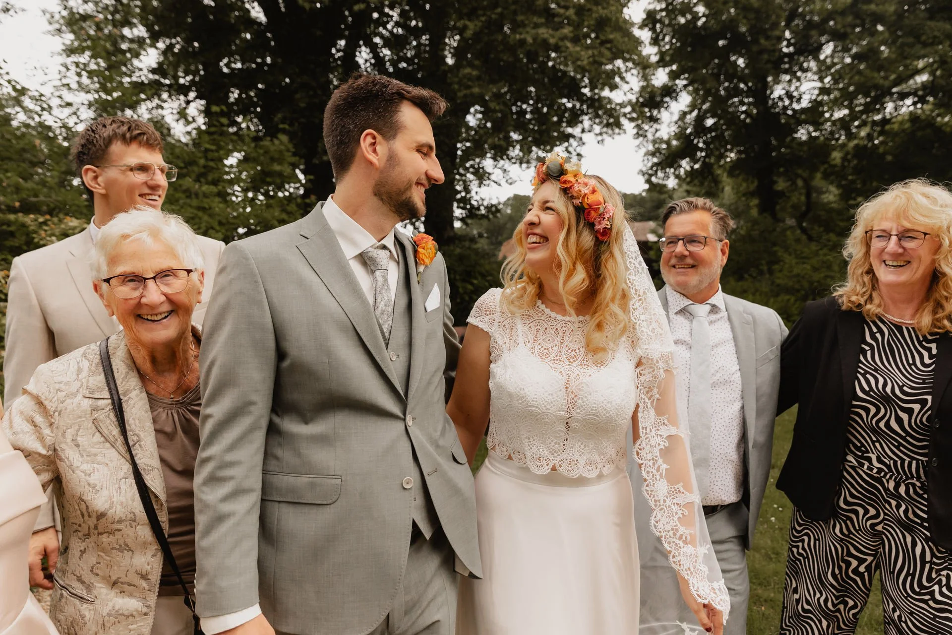Brautpaar lacht gemeinsam mit der Familie während einer sommerlichen Hochzeit in Lüneburg