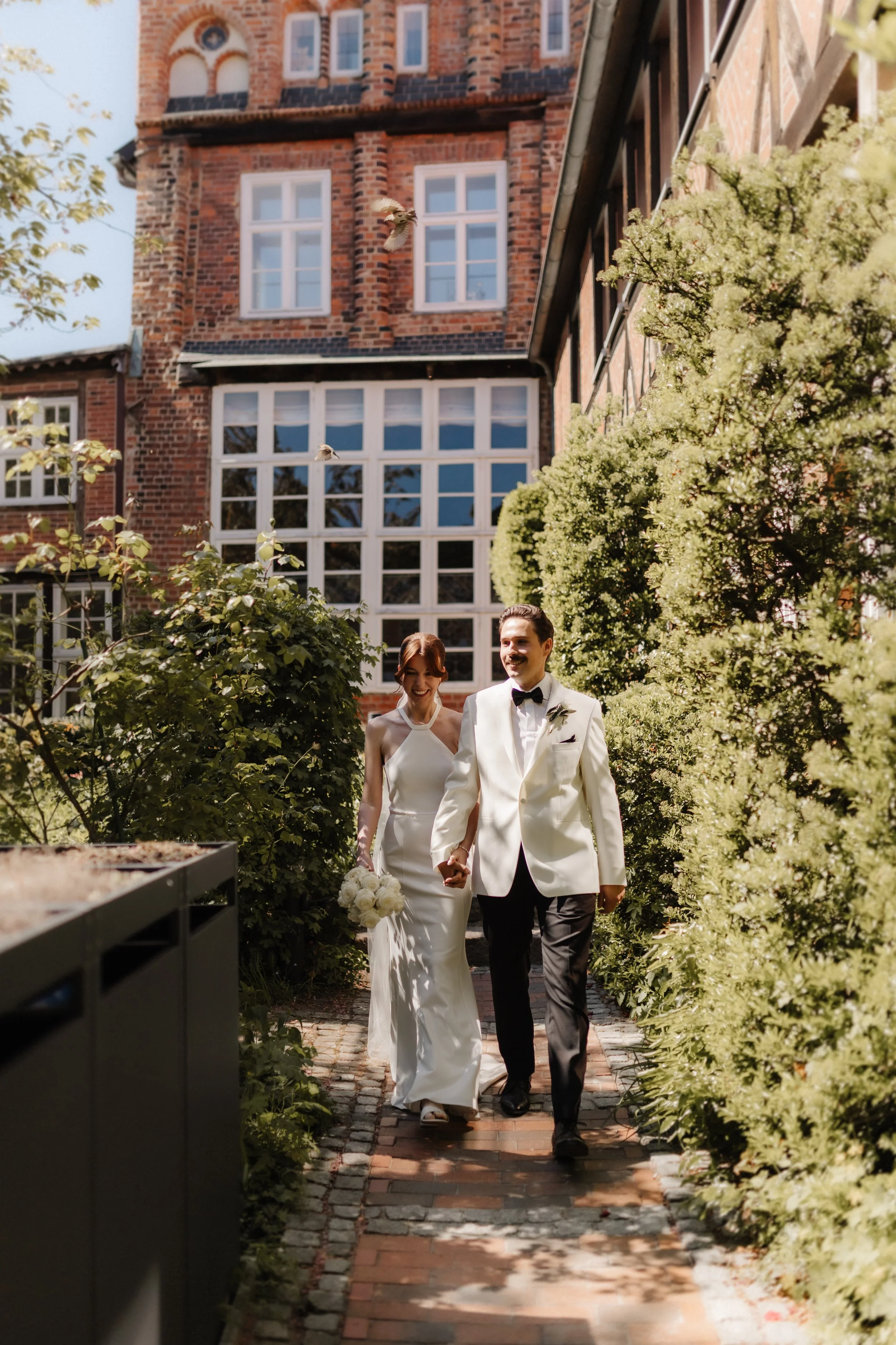 Frisch verheiratetes Brautpaar läuft Hand in Hand durch den Innenhof des Brömsehauses in Lüneburg.