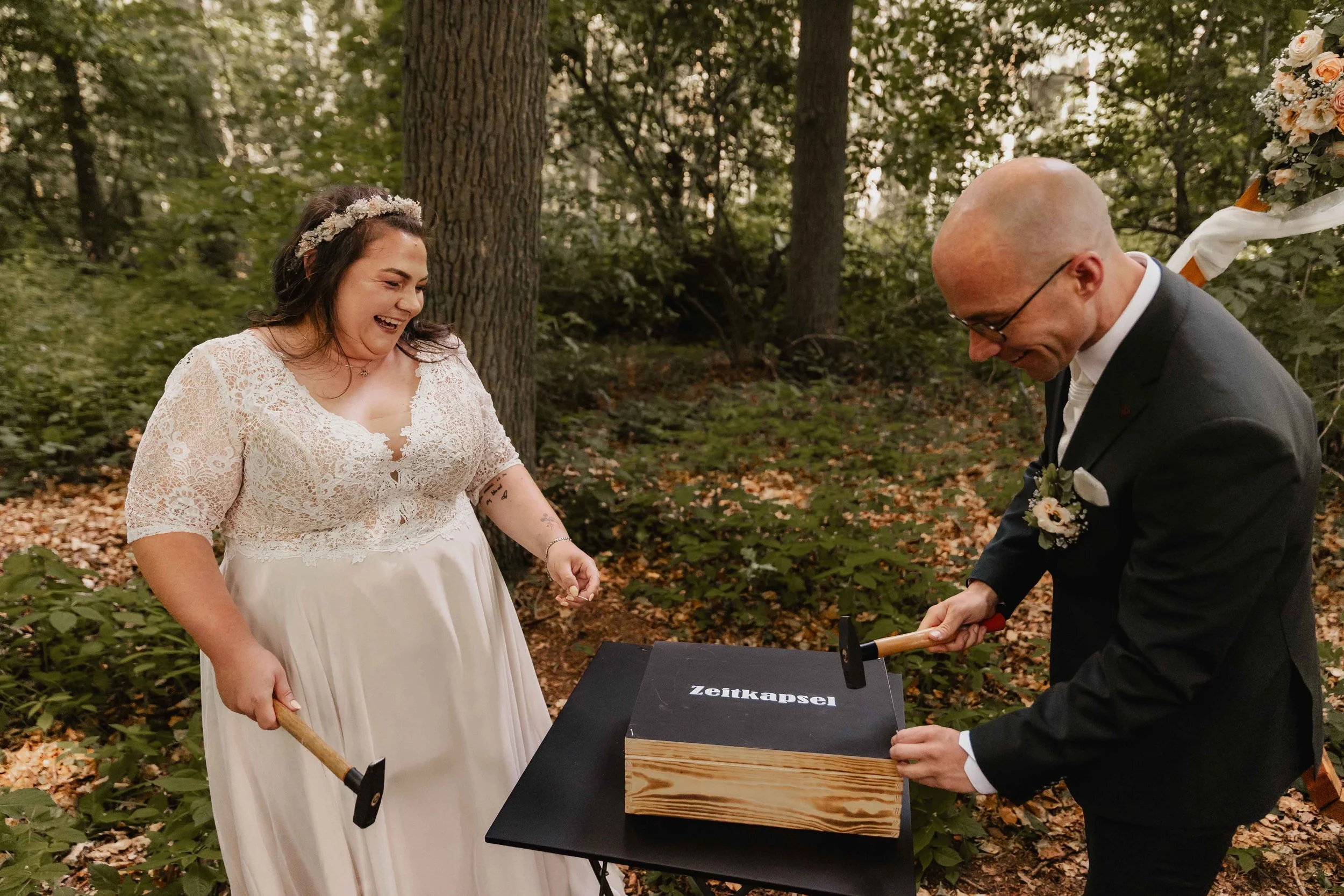 Braut und Bräutigam verschließen mit Hämmern eine Zeitkapsel bei ihrer Hochzeit