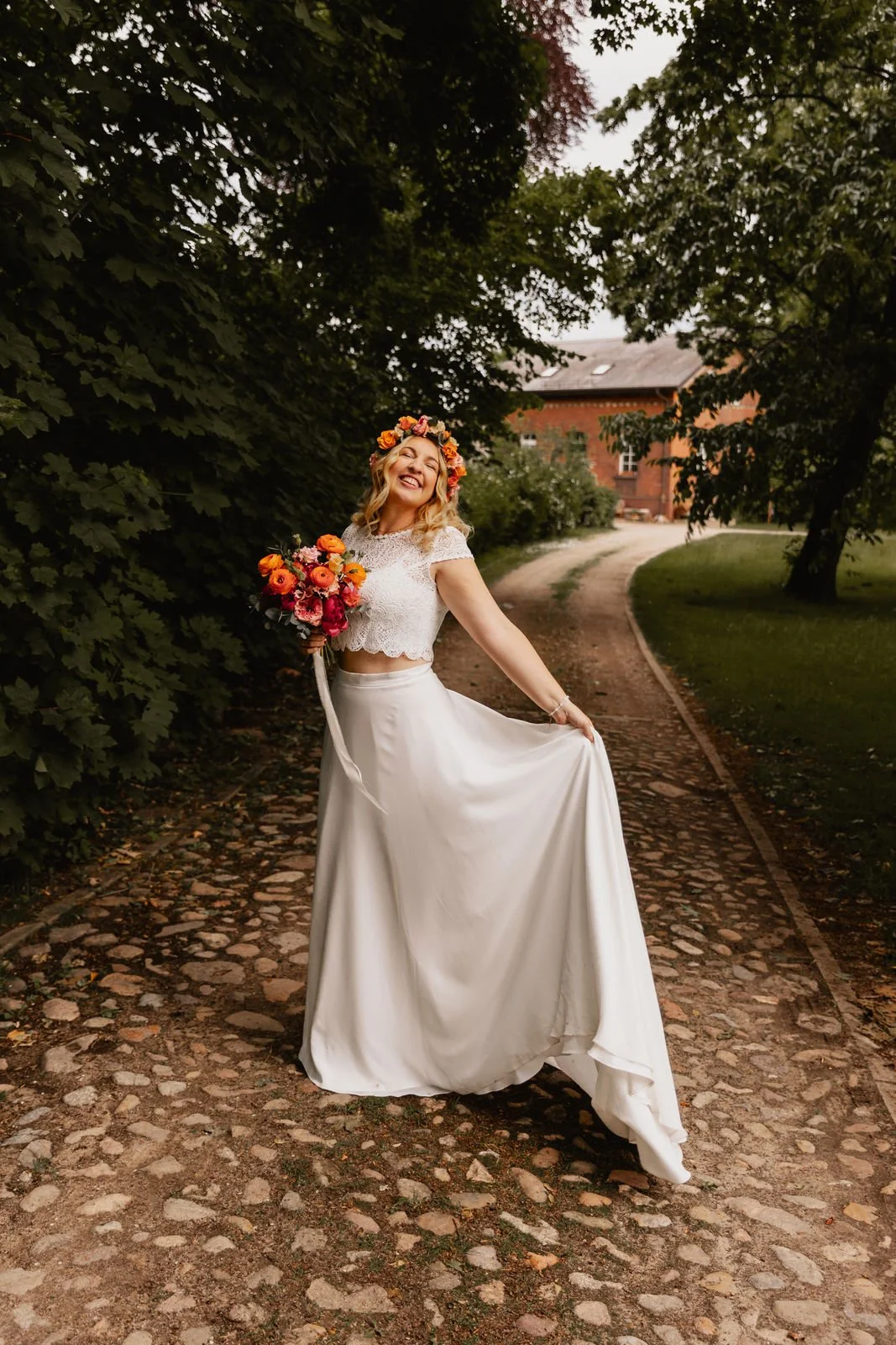 Braut mit Blumenstrauß und langem Kleid geht auf Kopfsteinpflasterweg in Lüneburg