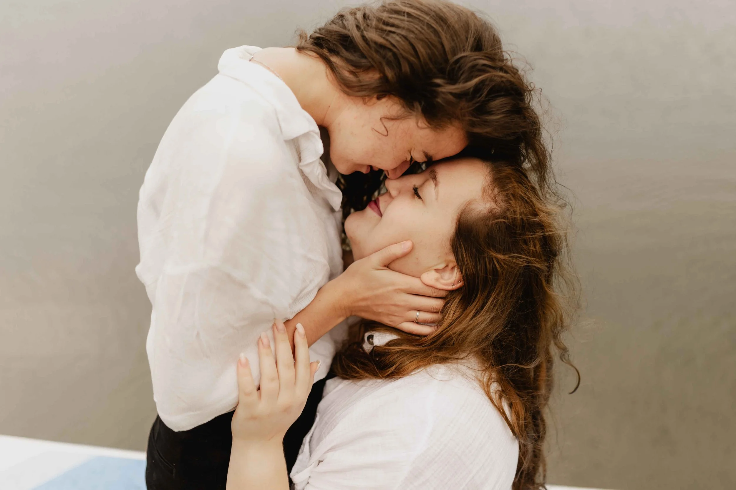 Zwei Frauen halten sich liebevoll am Gesicht und berühren ihre Stirn beim Umarmen auf einem SUP-Board