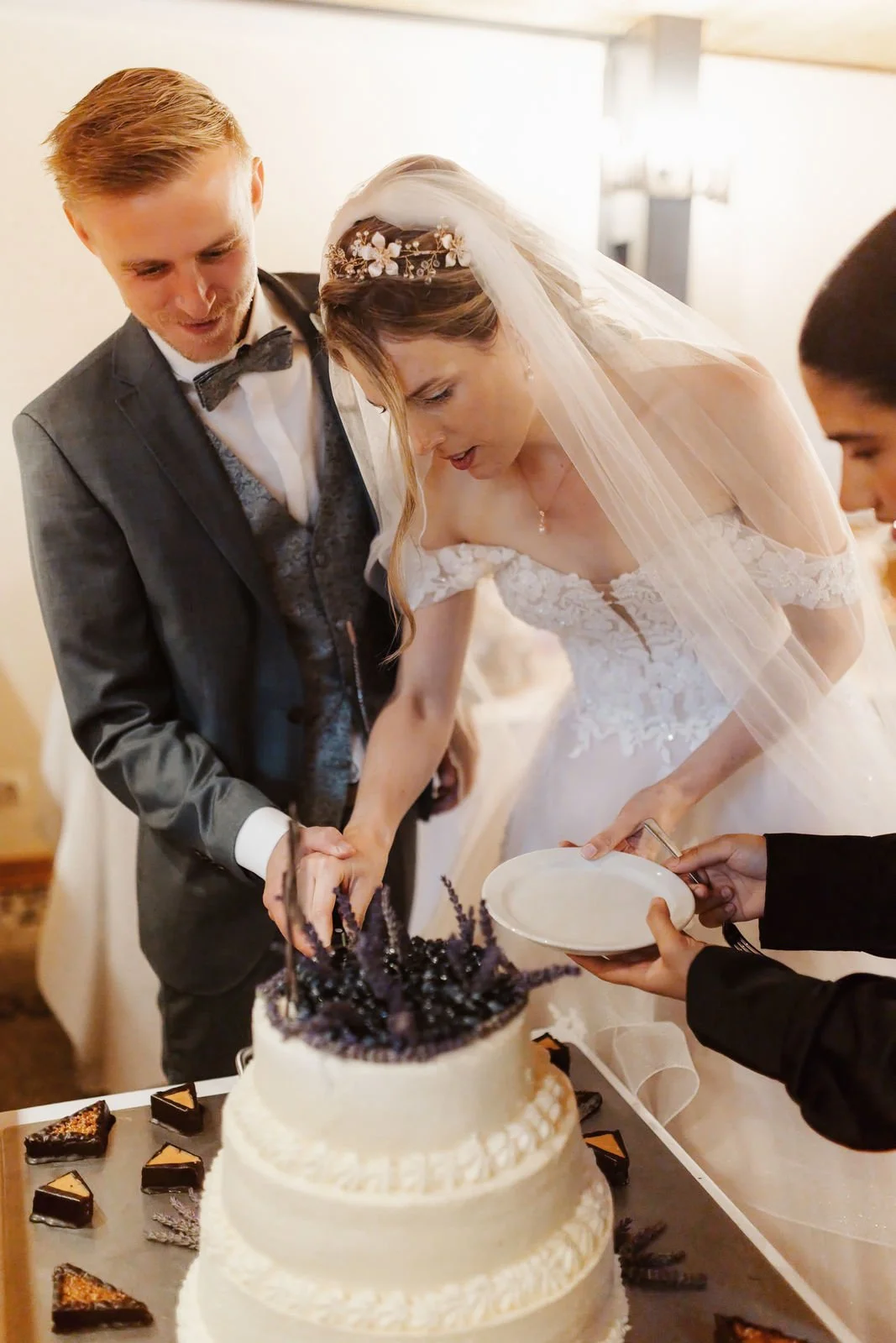Brautpaar schneidet gemeinsam die Hochzeitstorte mit Lavendeldekoration im Heide Hotel Reinstorf bei Lüneburg an – natürliche Hochzeitsfotografie voller besonderer Momente.