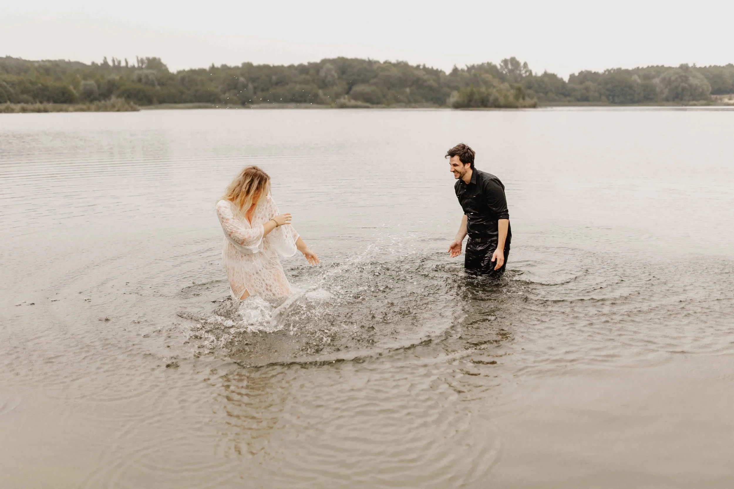 Paar spritzt spielerisch Wasser im See und genießt den Moment