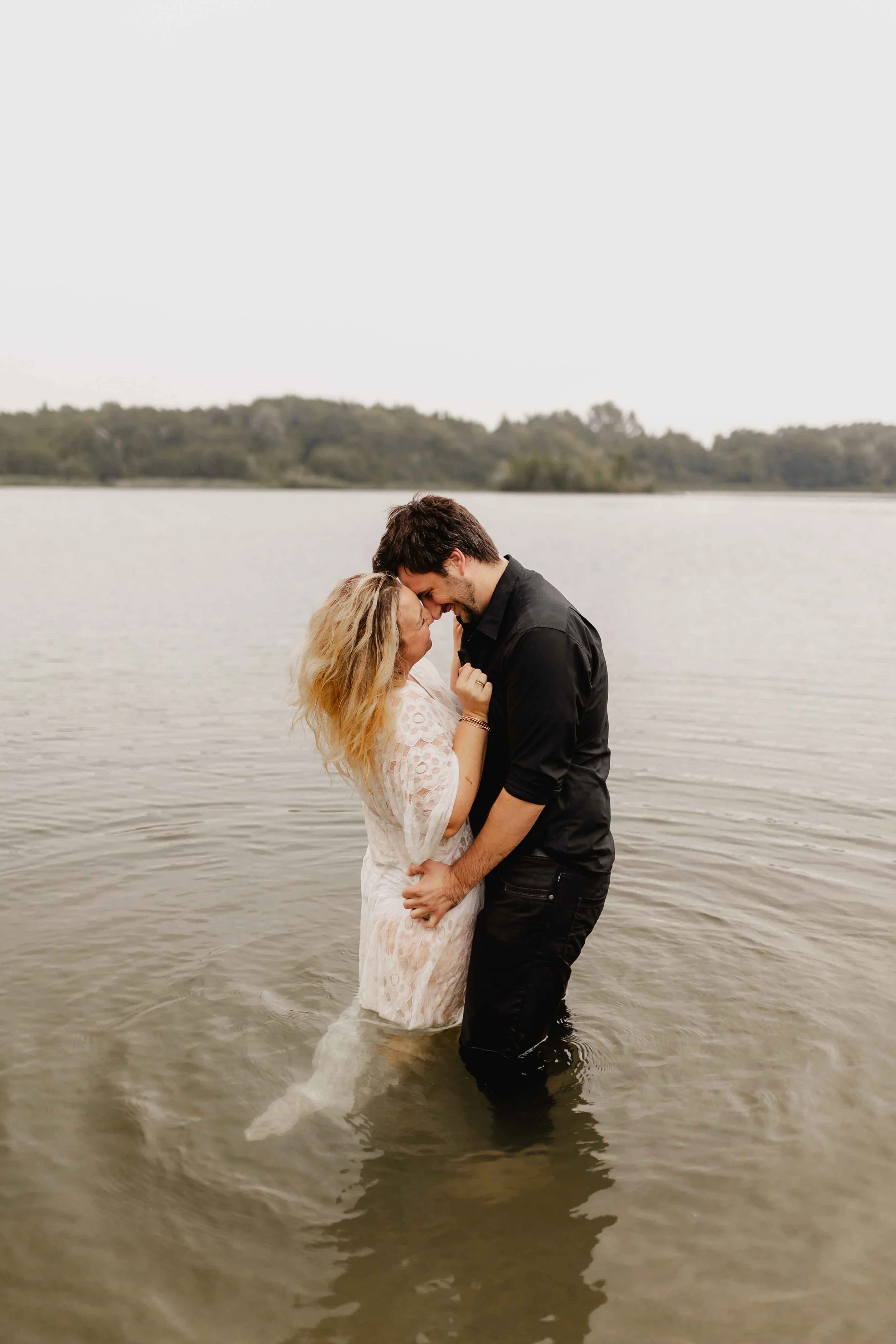 Paar steht eng umschlungen im See und küsst sich liebevoll im Wasser