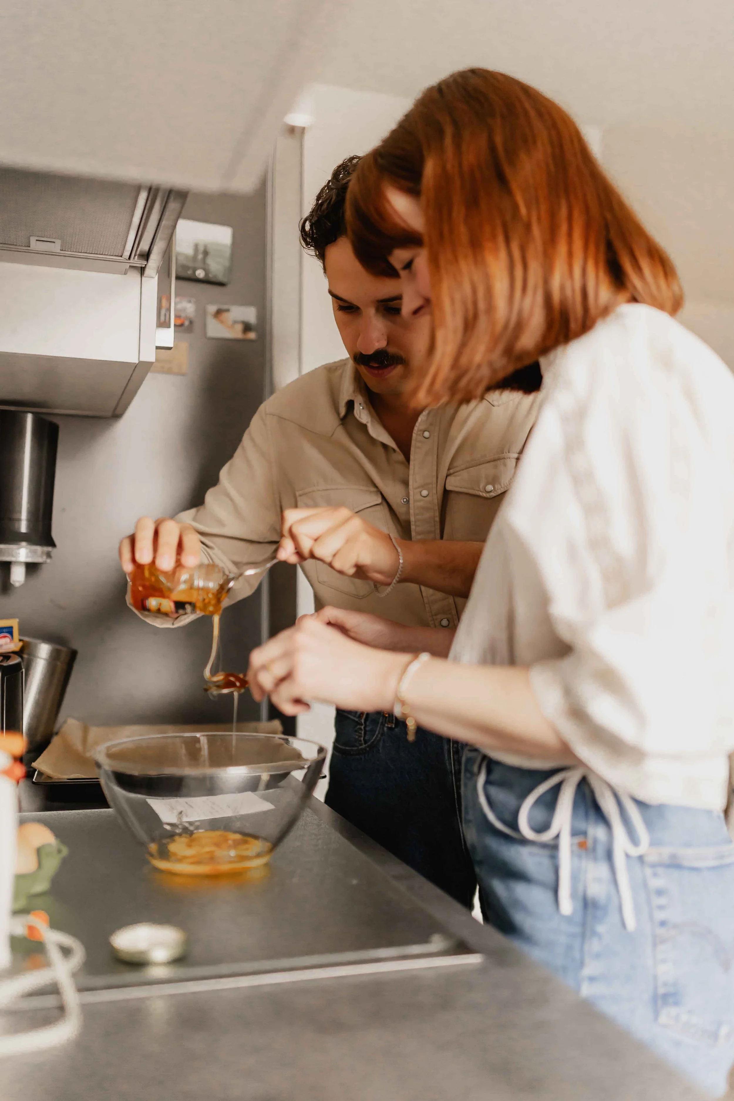Paar steht zusammen in der Küche, er gibt Gewürze in eine Schüssel, sie hält den Löffel bei einer Homestory in Lüneburg