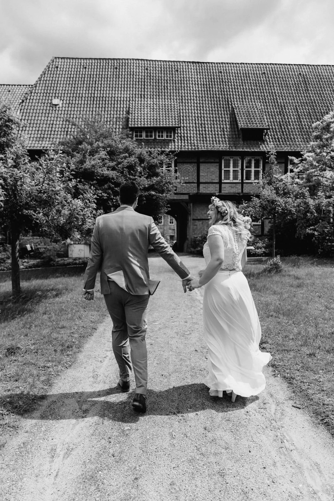 Braut und Bräutigam gehen Hand in Hand auf einem Weg in Lüneburg in Schwarz-Weiß