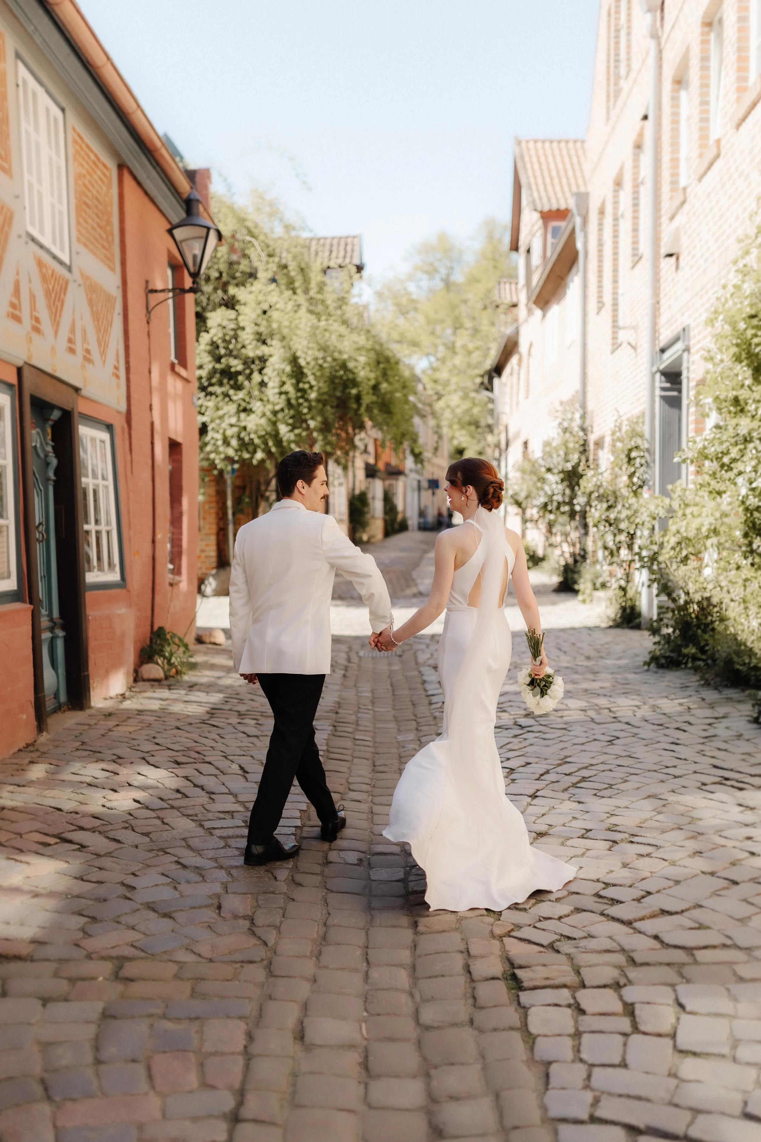 Brautpaar läuft nach seiner Hochzeit Hand in Hand durch eine historische Gasse in der Lüneburger Altstadt.