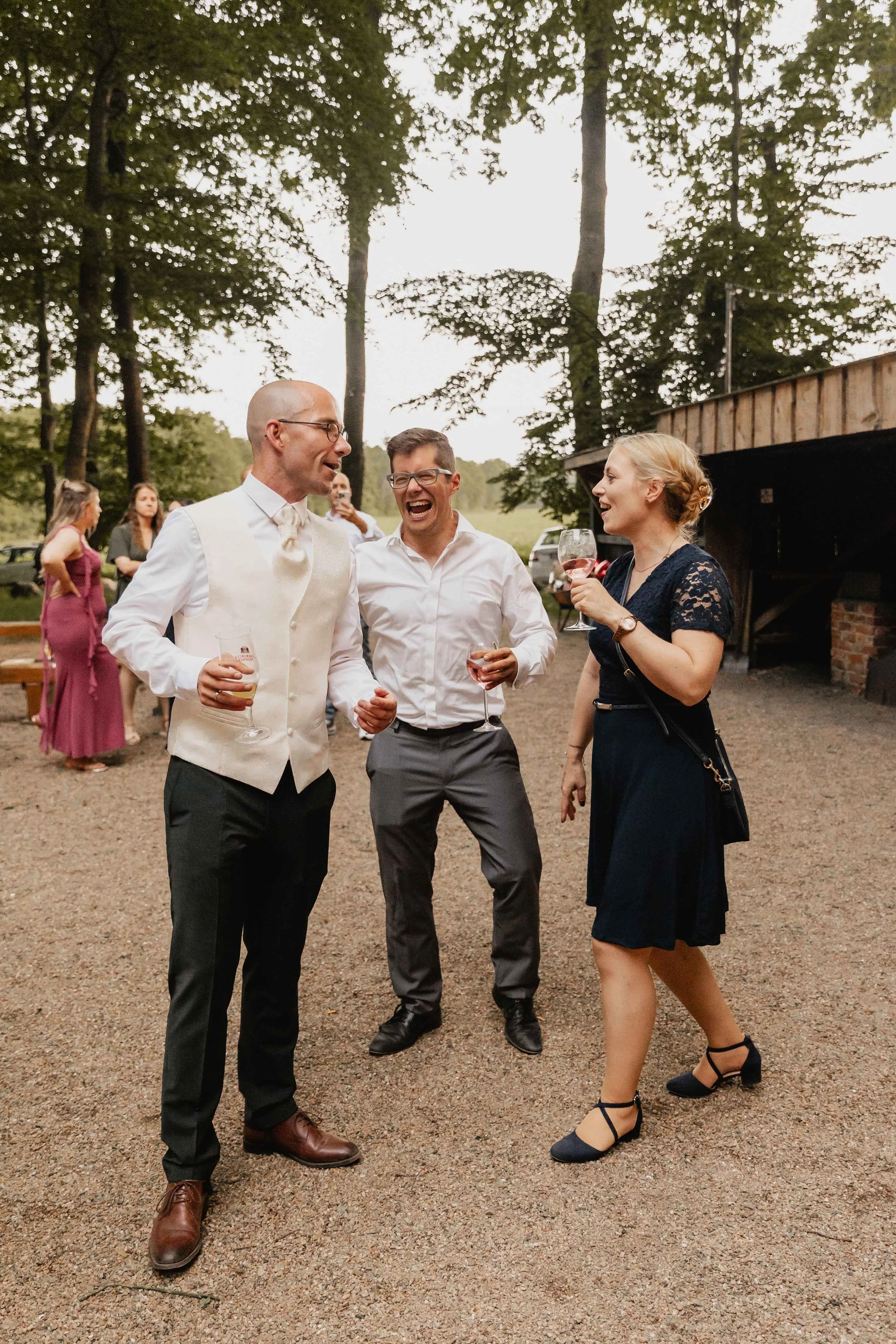 Bräutigam tanzt lachend mit zwei Gästen auf seiner Hochzeit