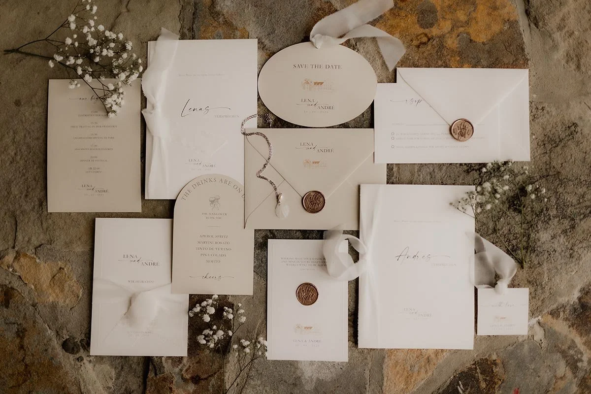Elegante Hochzeitspapeterie mit Einladungen, Karten und Briefumschlägen mit Wachssiegeln, arrangiert mit Schleierkraut auf rustikalem Untergrund