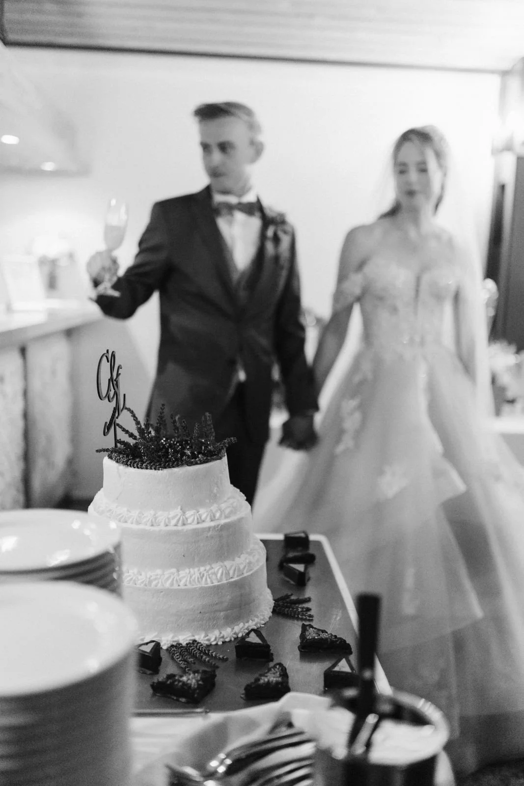 Brautpaar stößt mit Sekt vor der Hochzeitstorte im Heide Hotel Reinstorf bei Lüneburg an – ein authentischer Moment der Hochzeitsreportage in Schwarz-Weiß.