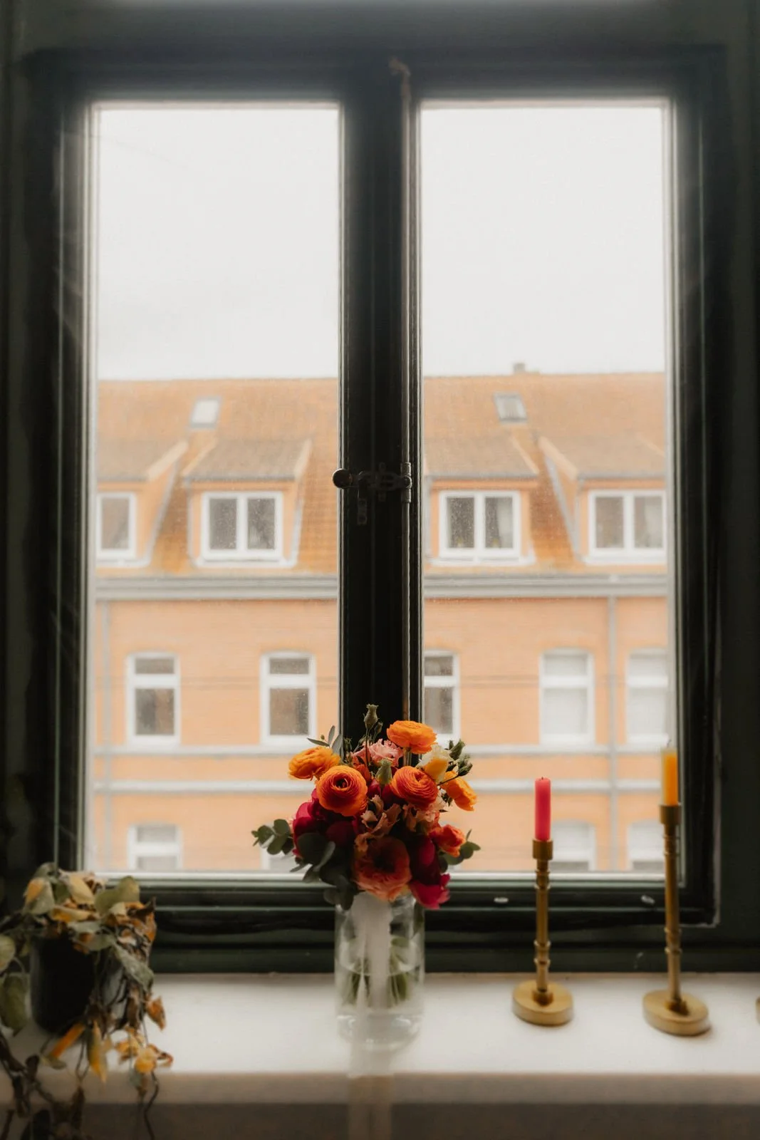 Stimmungsvolle Fensterdekoration beim Getting Ready in Lüneburg mit Blumenstrauß, Kerzen und Blick auf Altbauten