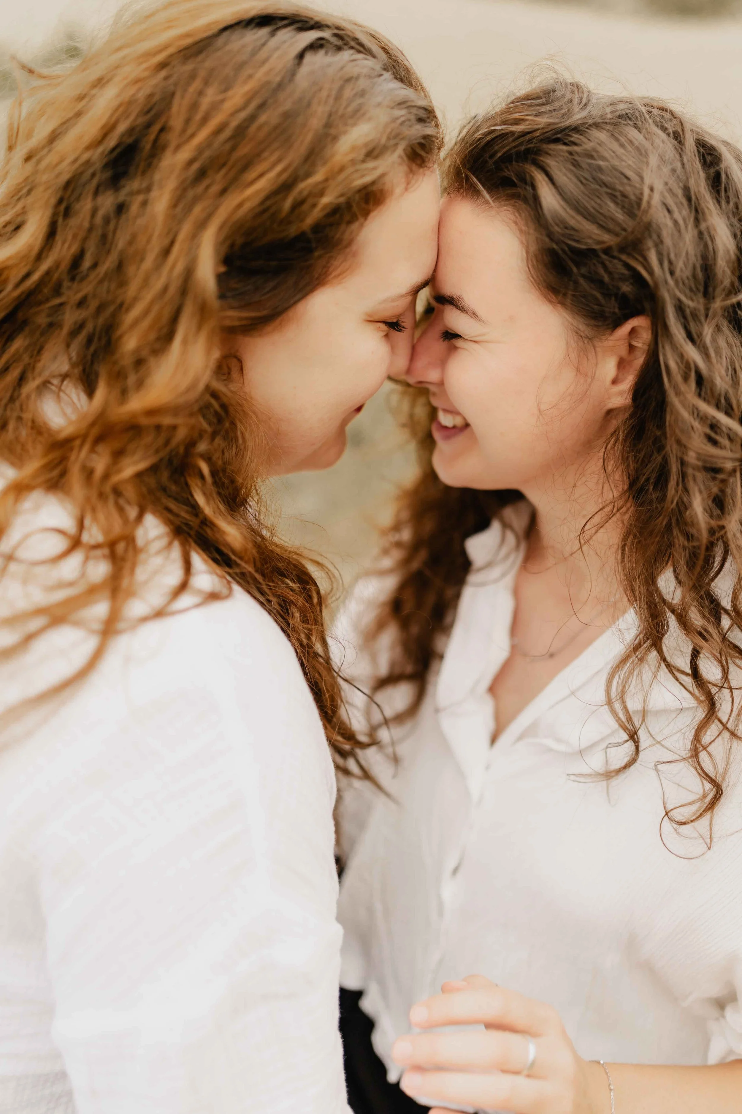 Zwei Frauen stehen Stirn an Stirn und lachen sich herzlich an