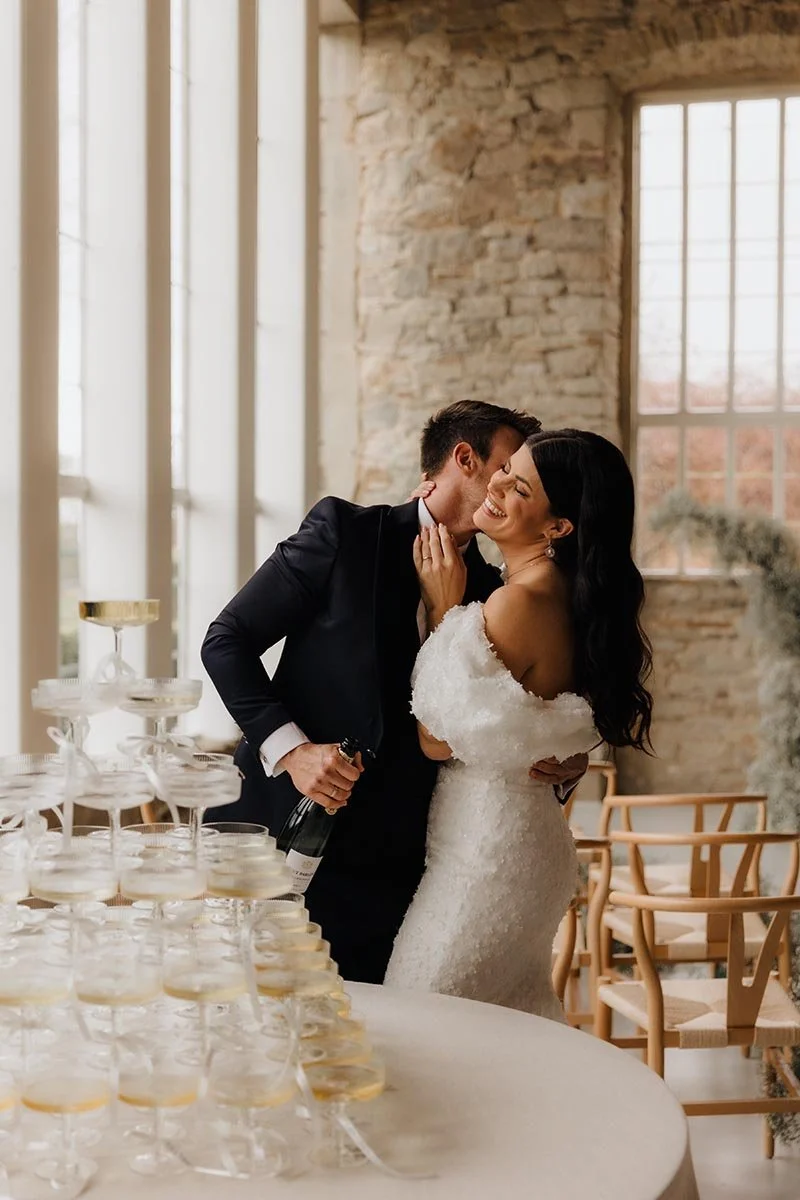 Brautpaar beim Sektempfang mit Champagner und liebevollem Kuss – elegante Hochzeitsfeier, echte Emotionen und natürliche Hochzeitsfotografie in Lüneburg